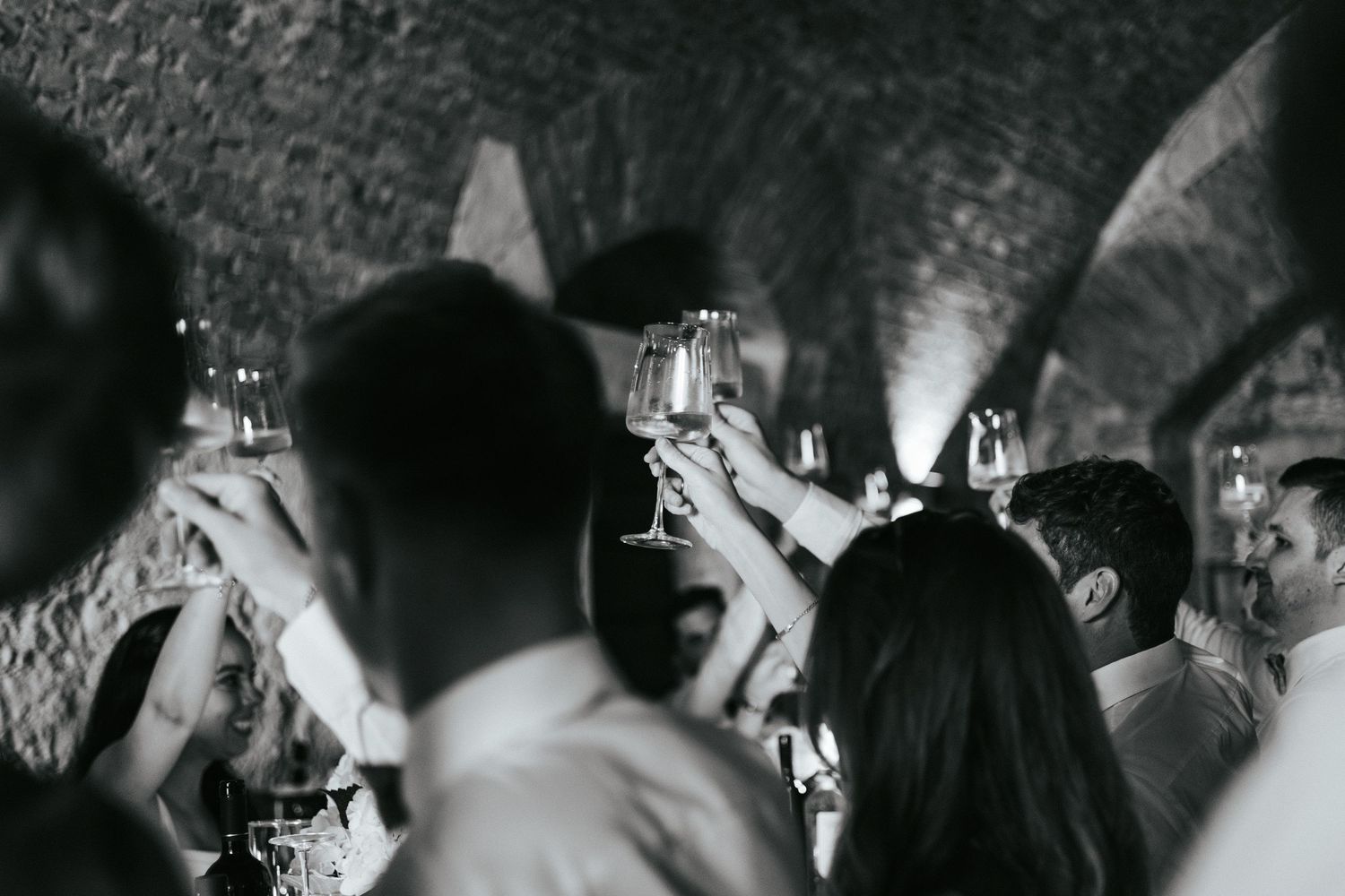 Black and white photo of wedding guests celebrating during an indoor reception.