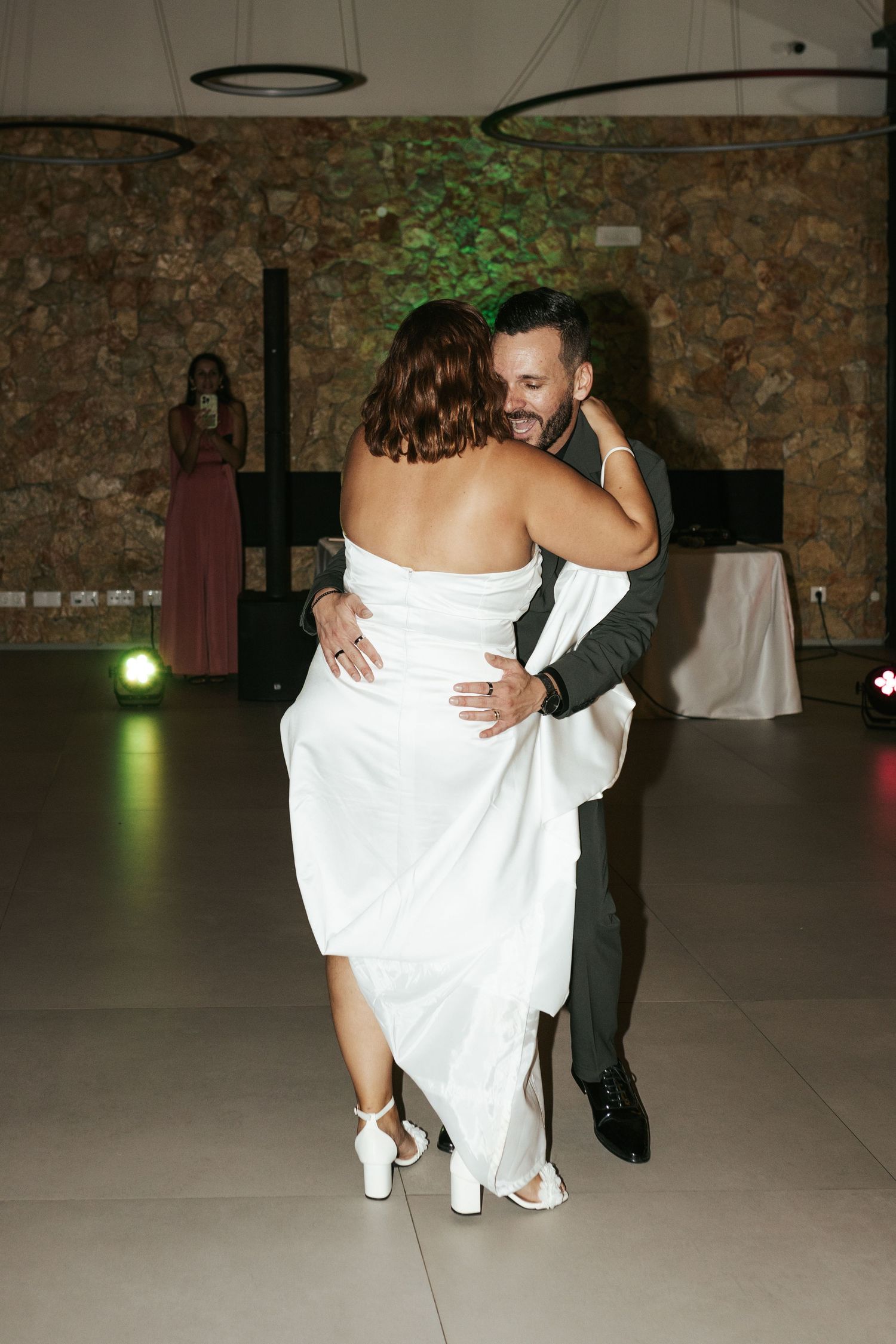 Couple dancing intimately at wedding reception with bride wearing white dress and groom in black suit.