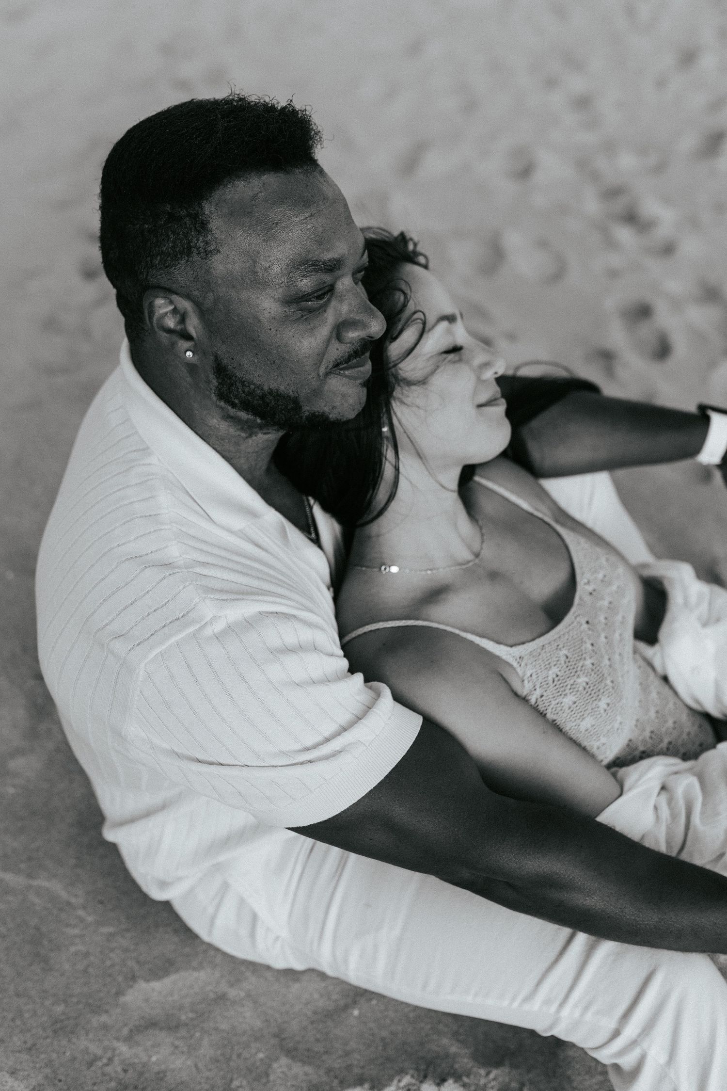 An intimate black and white portrait of a couple relaxing together on the beach. Praia do Porto de Mós, Lagos, Algarve, Portugal.