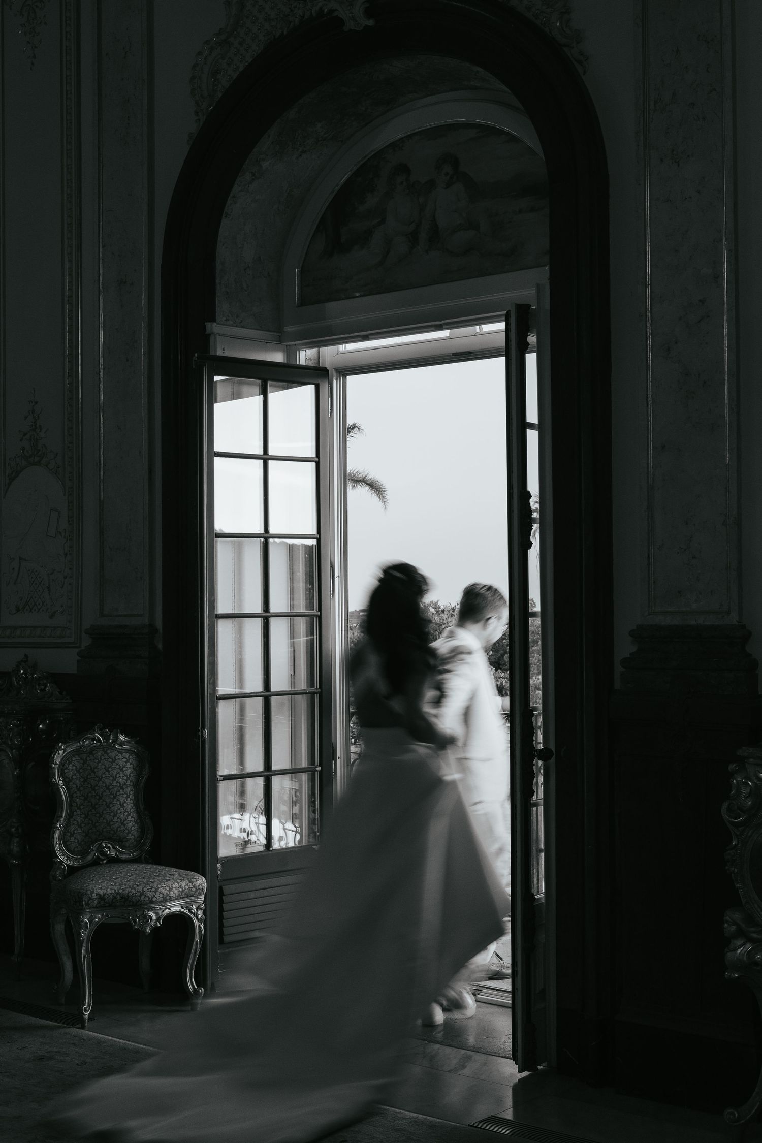 Dramatic black and white silhouette through arched doorway in an elegant venue with flowing dress.