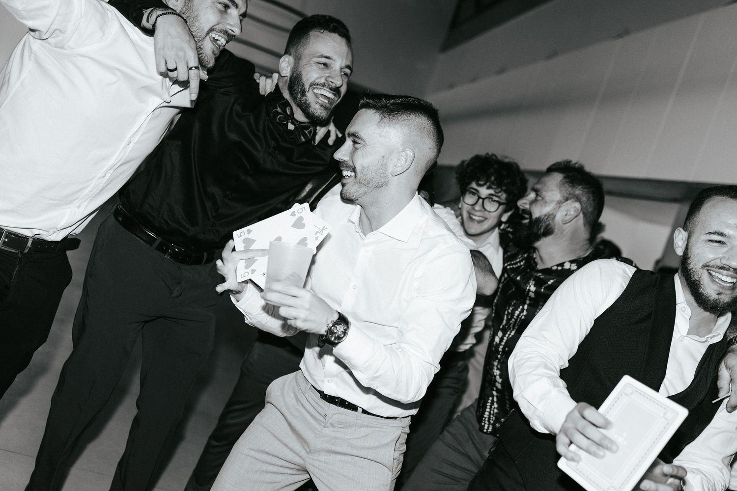 Black and white photo of people dancing and celebrating at a wedding reception.