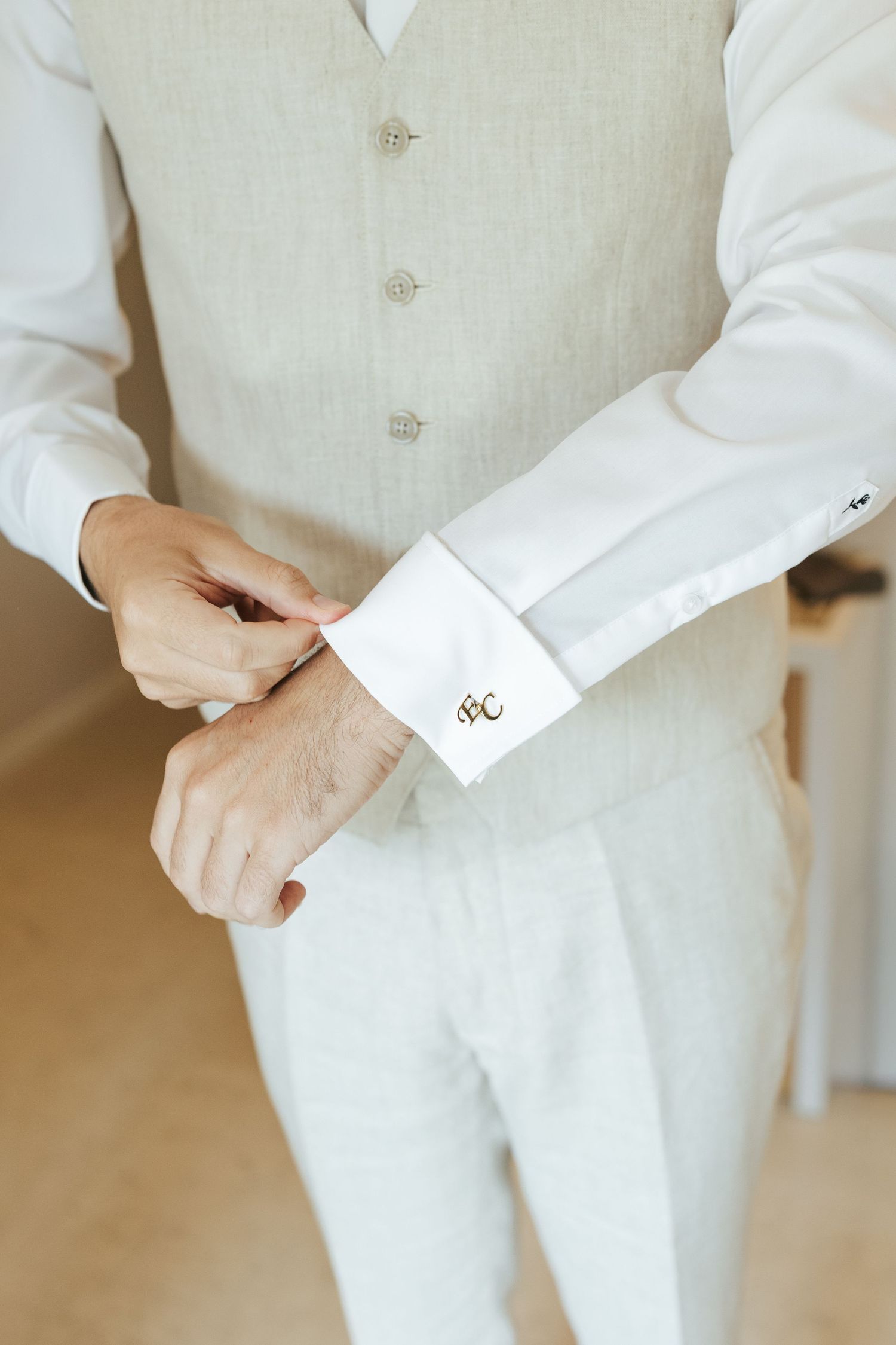 Details of a cream colored formal vest with buttons and cufflinks.