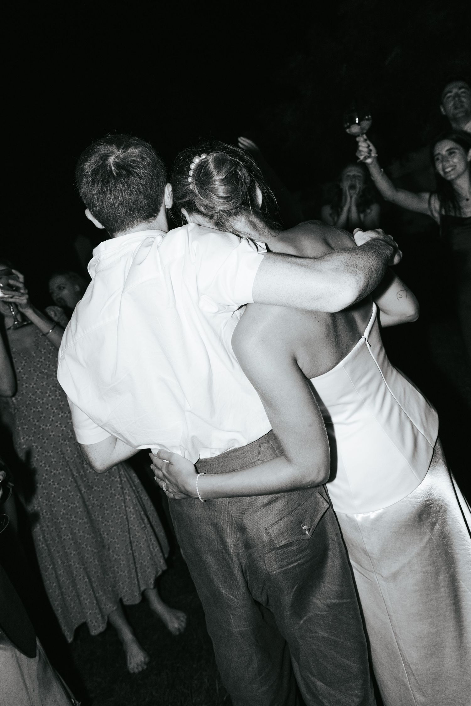 Couple embracing and dancing together at a nighttime outdoor wedding reception.