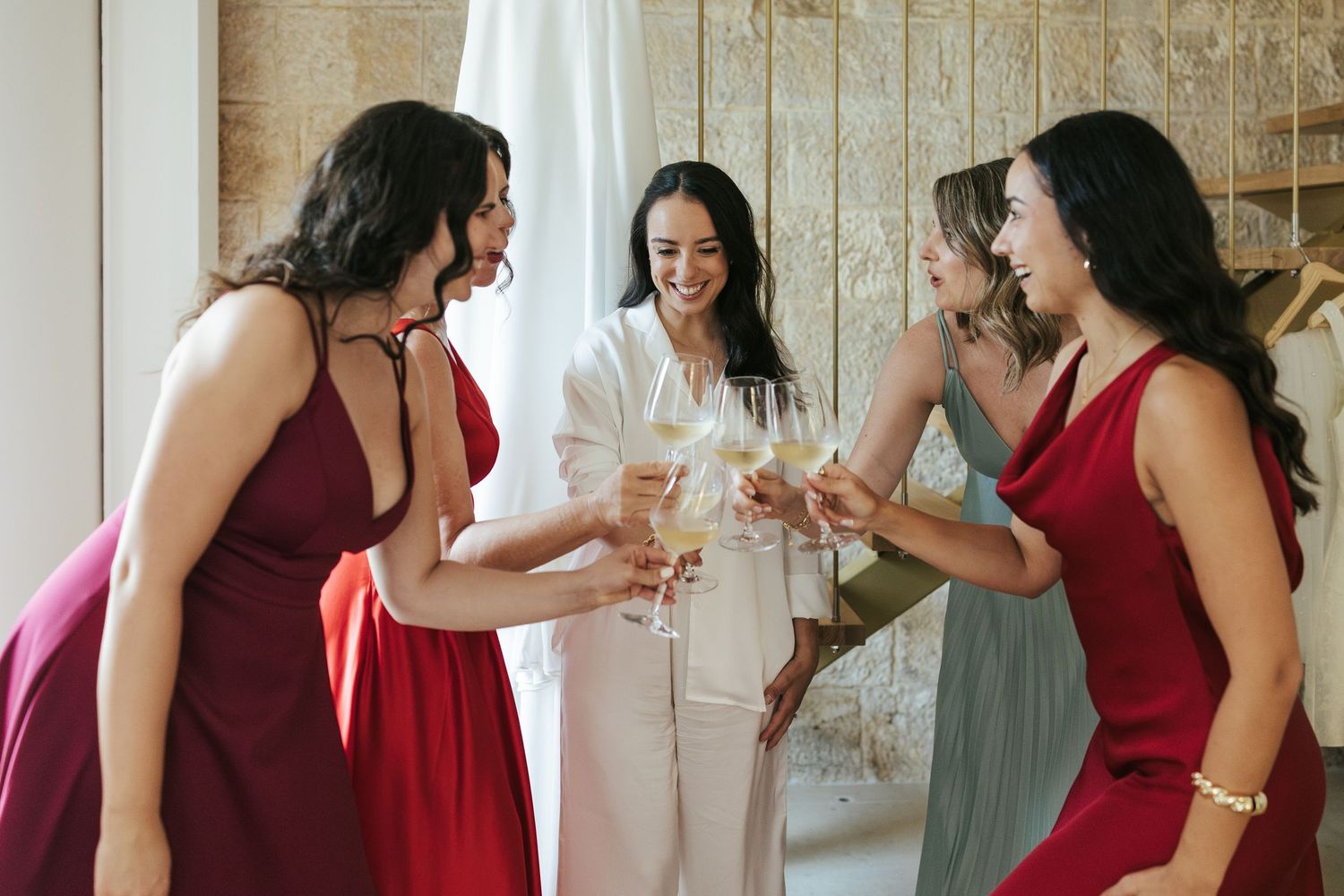 Bridesmaids in burgundy dresses gather together during a wedding celebration.
