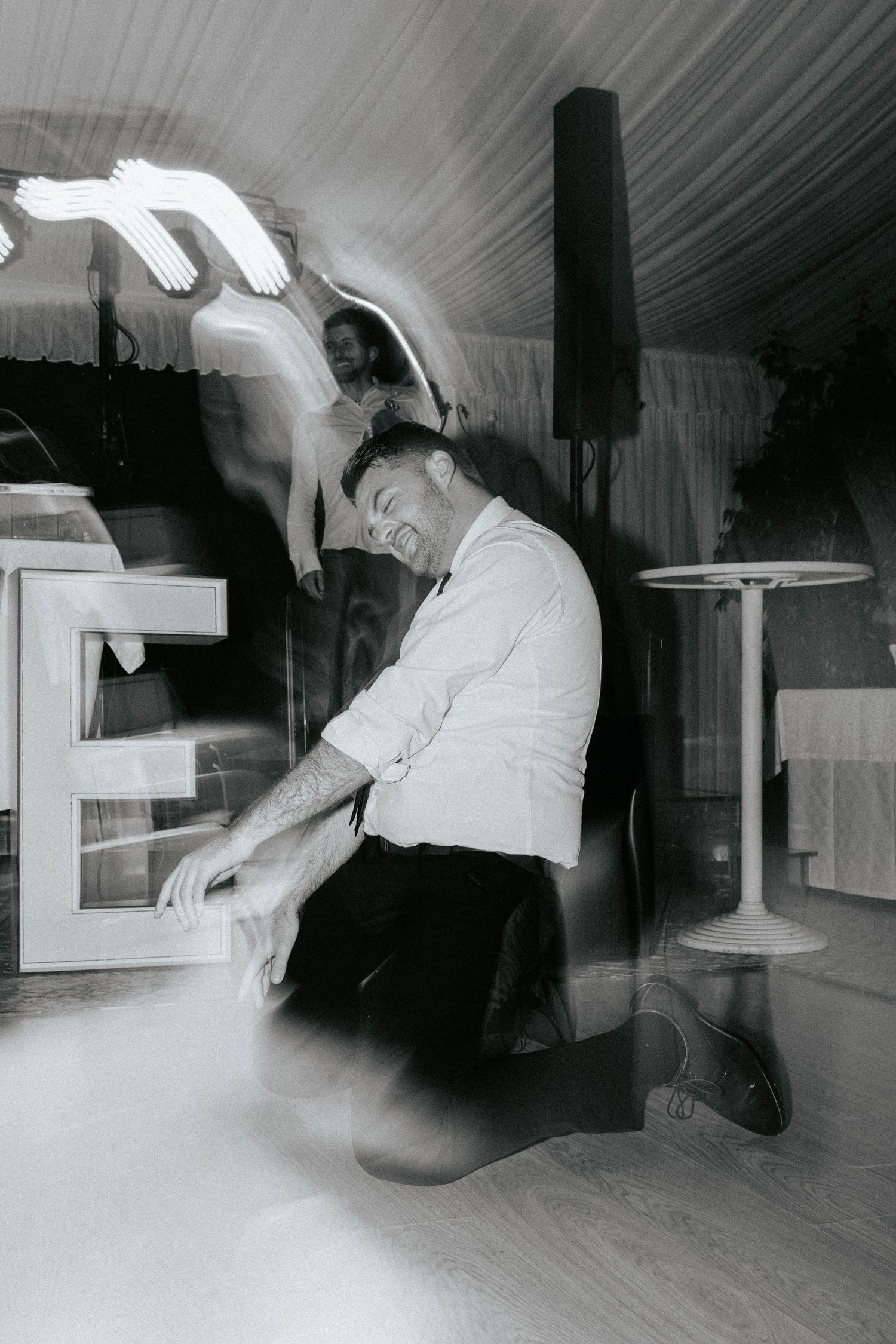 Black and white photo taken at a nightclub showing a person kneeling down by what appears to be lighting equipment.