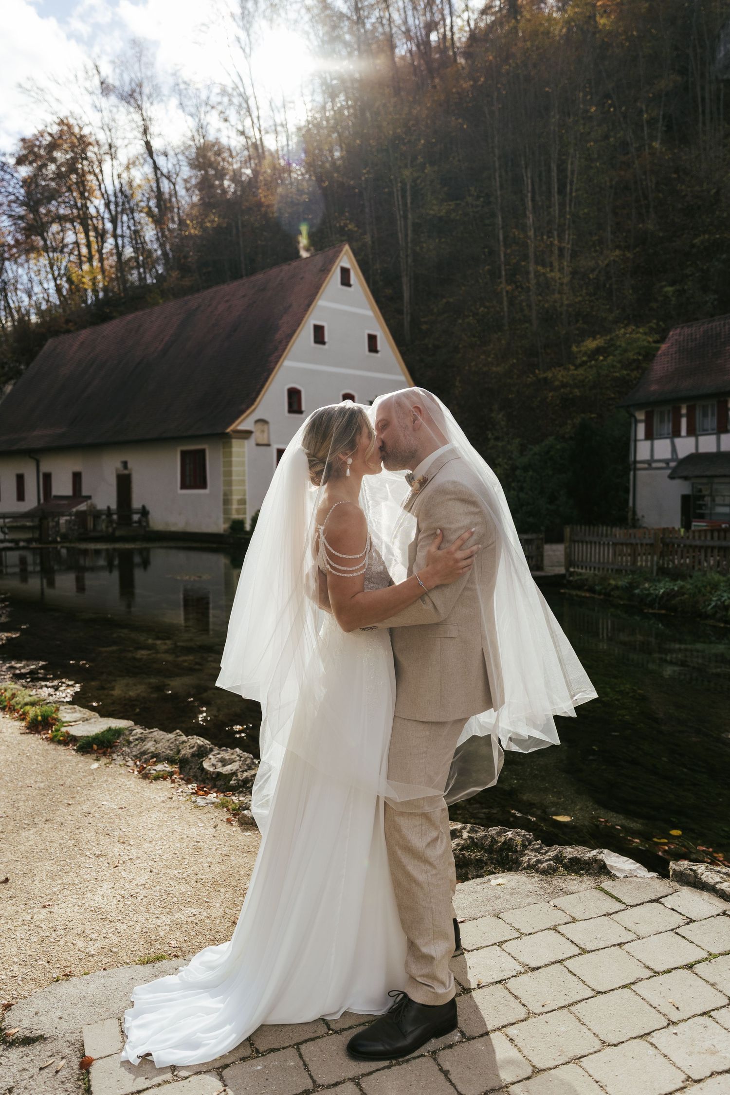 A romantic wedding moment captured outside rustic white cabins in a wooded setting.