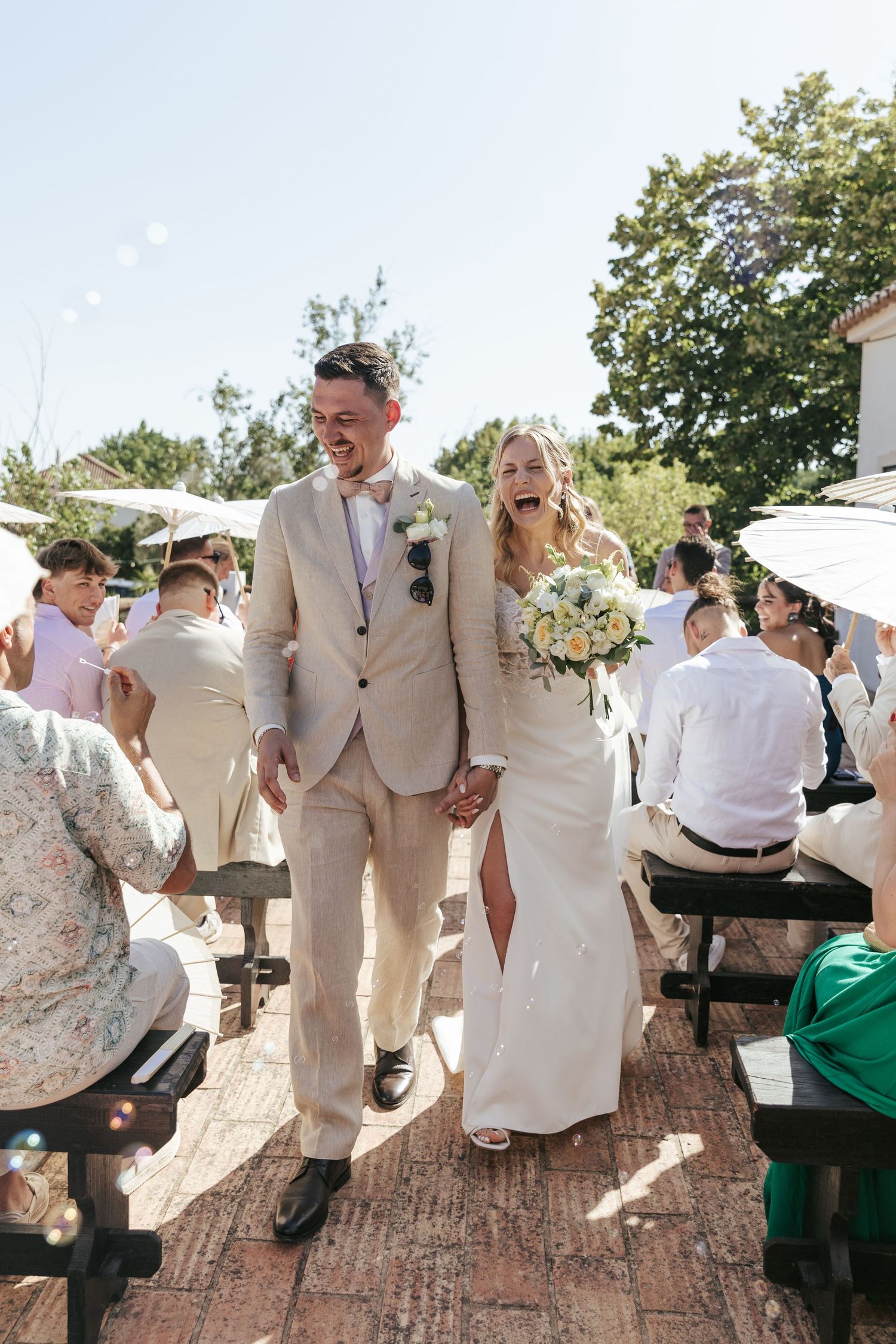 Wedding guests dance and celebrate on a brick patio during an outdoor summer reception.