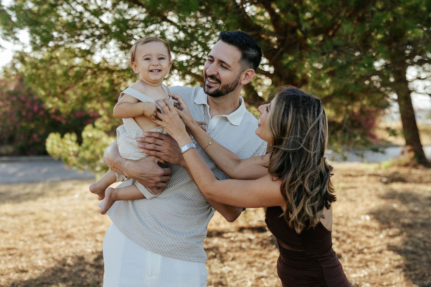 A family shares a joyful moment together outdoors in warm sunlight among trees in a natural setting.