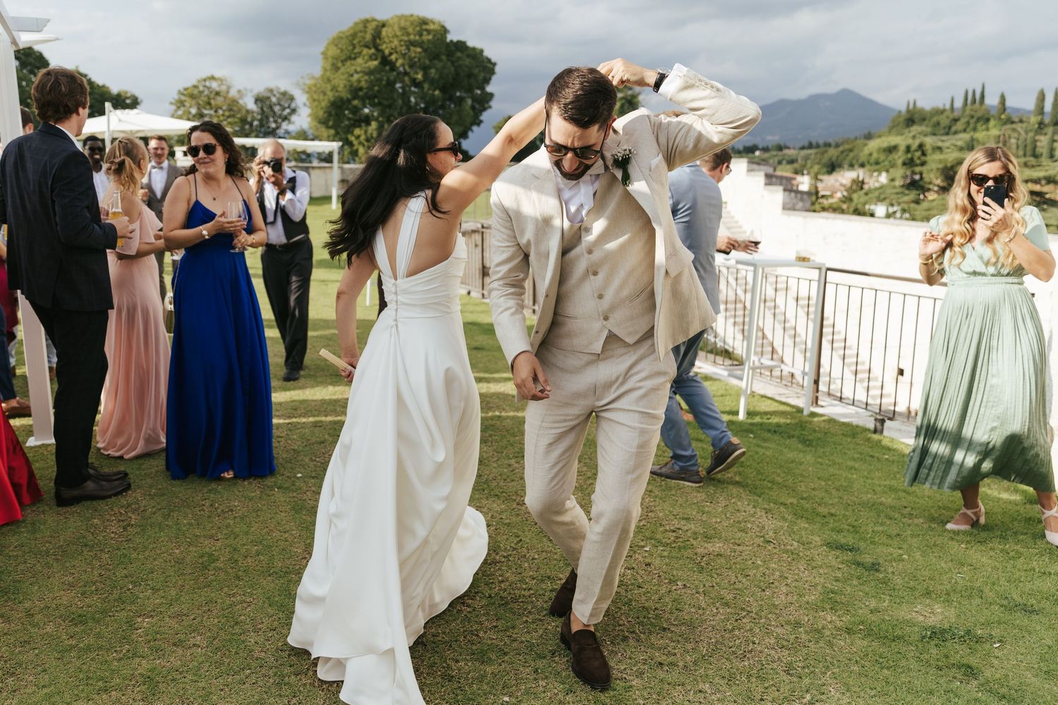 Guests mingle and celebrate at an elegant outdoor wedding reception with white decor and mountain views.