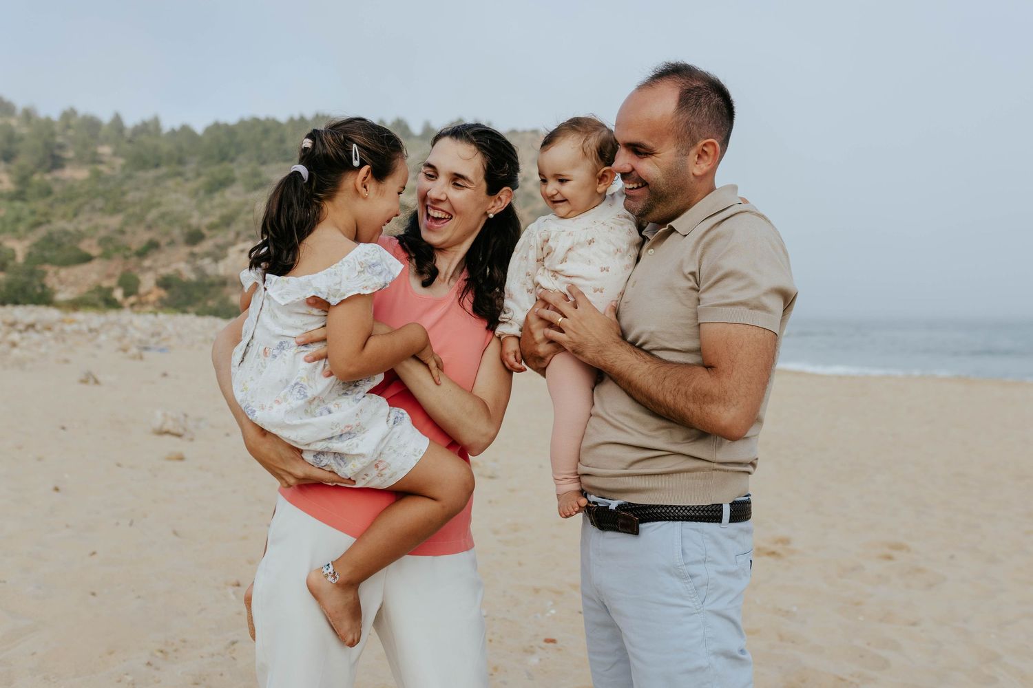 Family enjoying a sunny day together at the beach with natural expressions and casual attire.