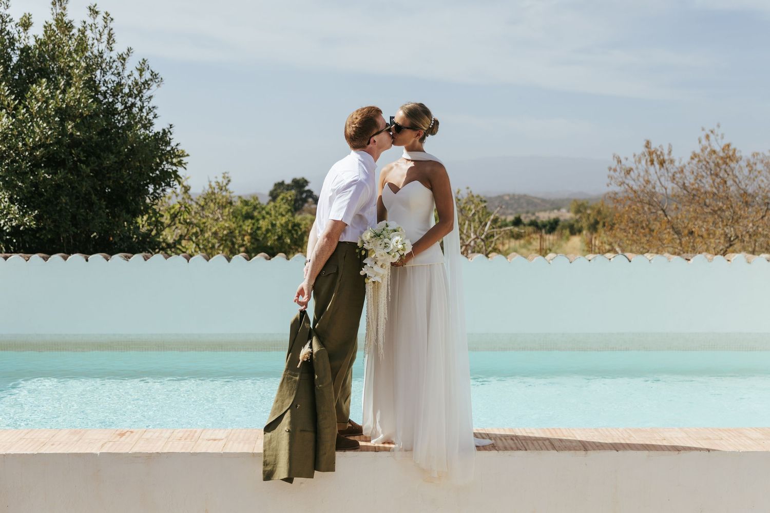 Two people share a romantic moment by a turquoise pool. Photo taken at Morgado do Quintão, Portugal.