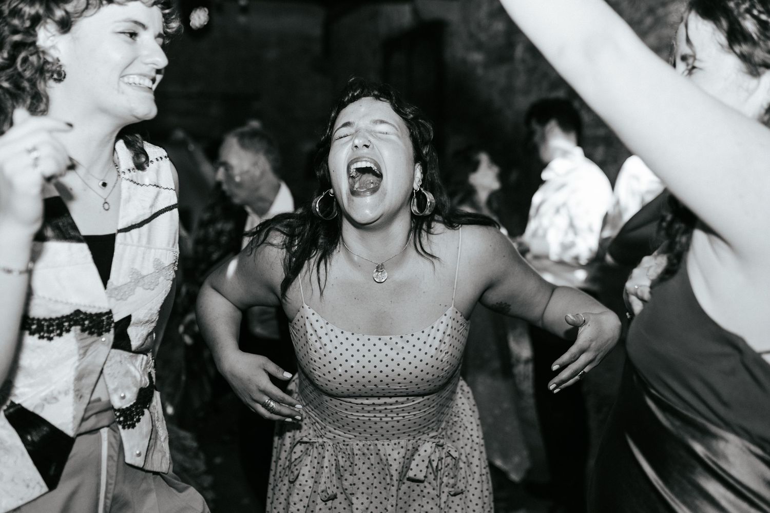 Black and white photo showing people dancing and laughing joyfully at what appears to be a lively party or celebration.