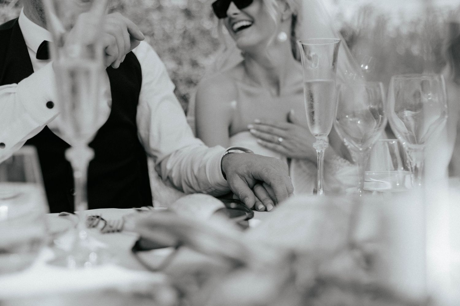 Black and white photo of a couple enjoying champagne at an elegant wedding reception table.