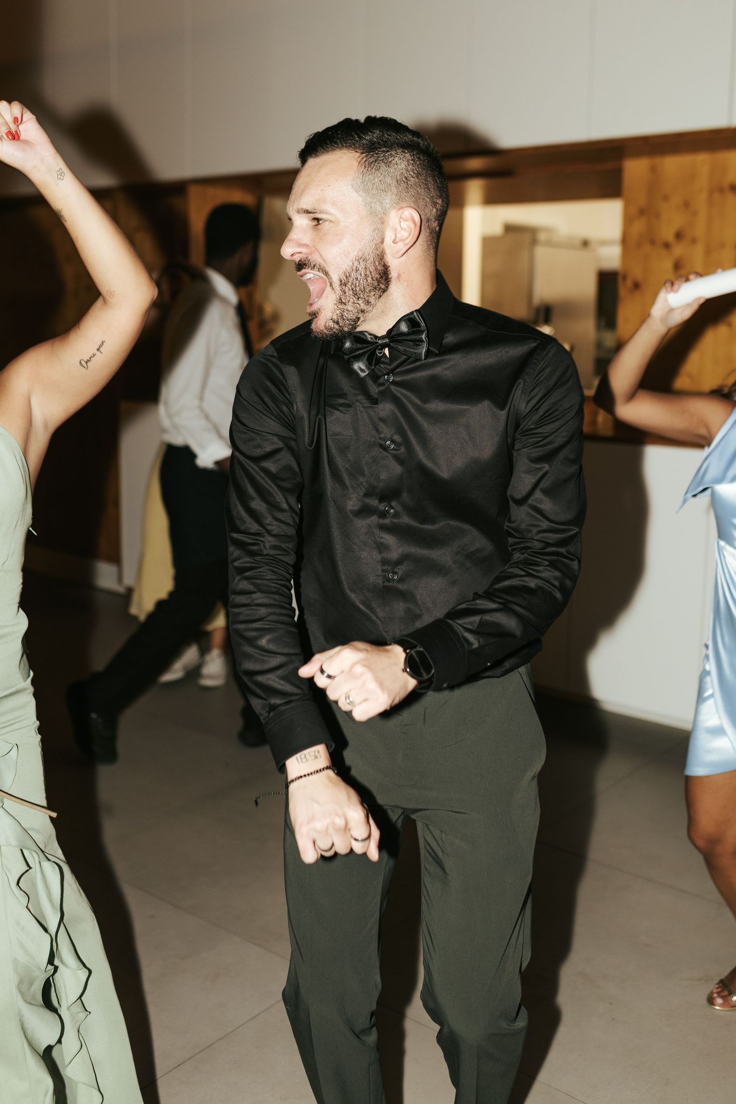 Person in black shirt dancing and smiling at what appears to be a celebration or party.