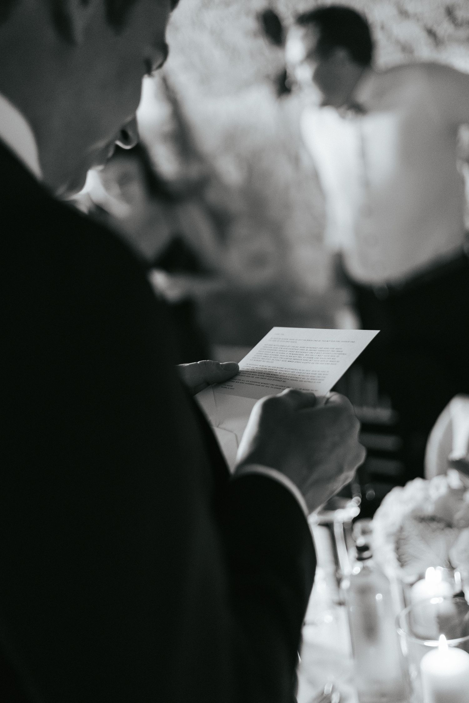 Black and white close-up of hands holding papers during a wedding ceremony.