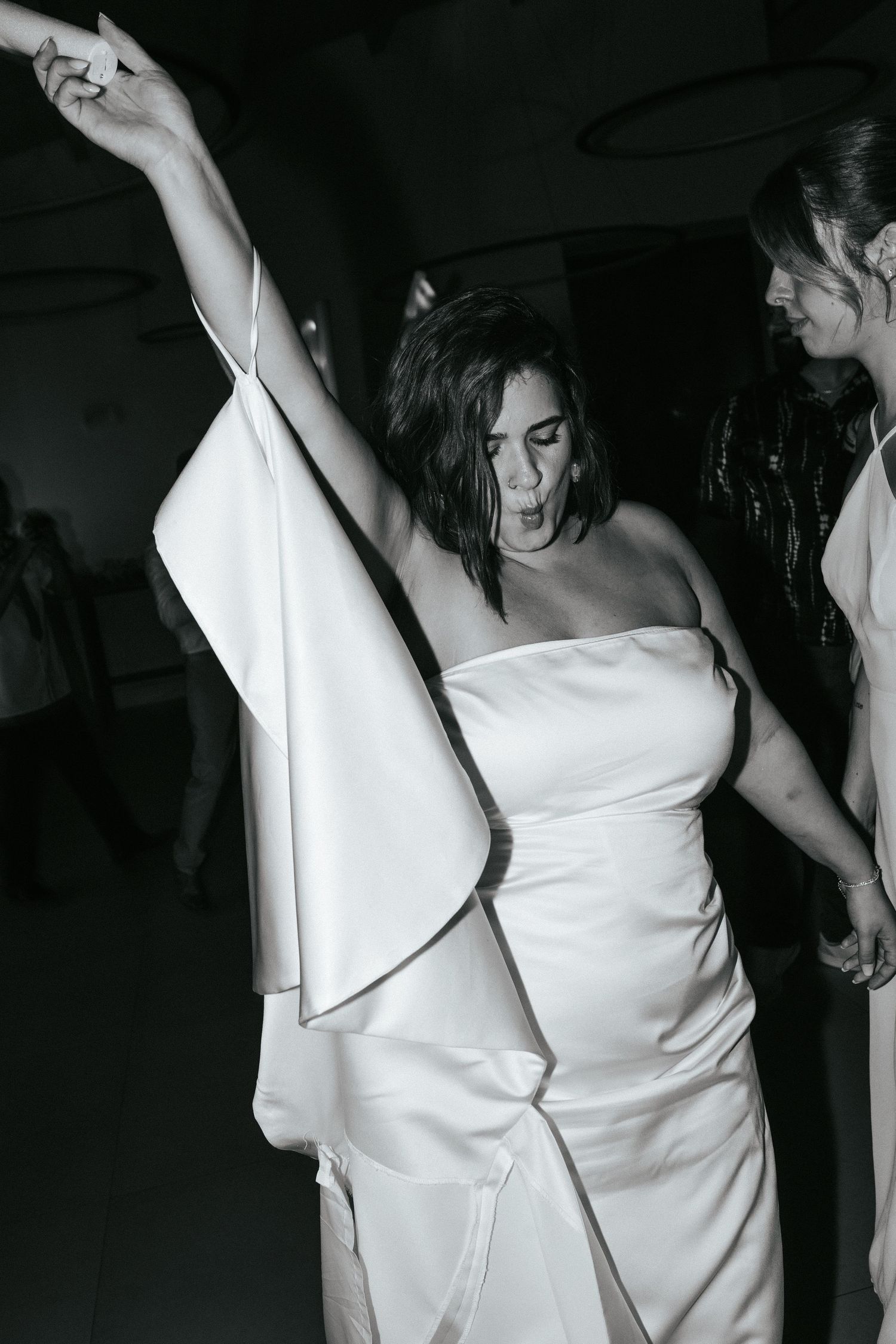 Someone dances enthusiastically in a white dress at what appears to be a wedding reception or celebration.