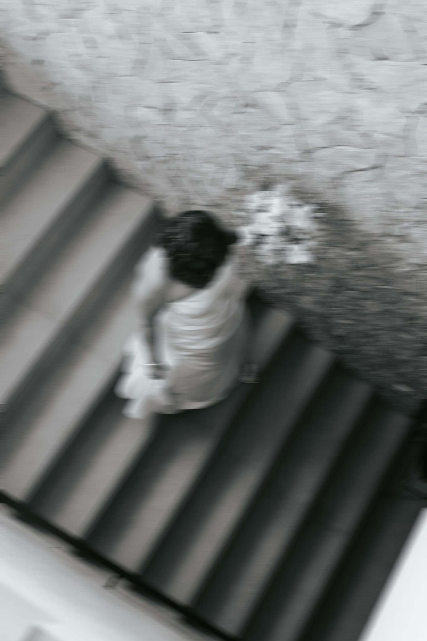 A blurred black and white image showing someone descending stairs in an artistic motion photograph.