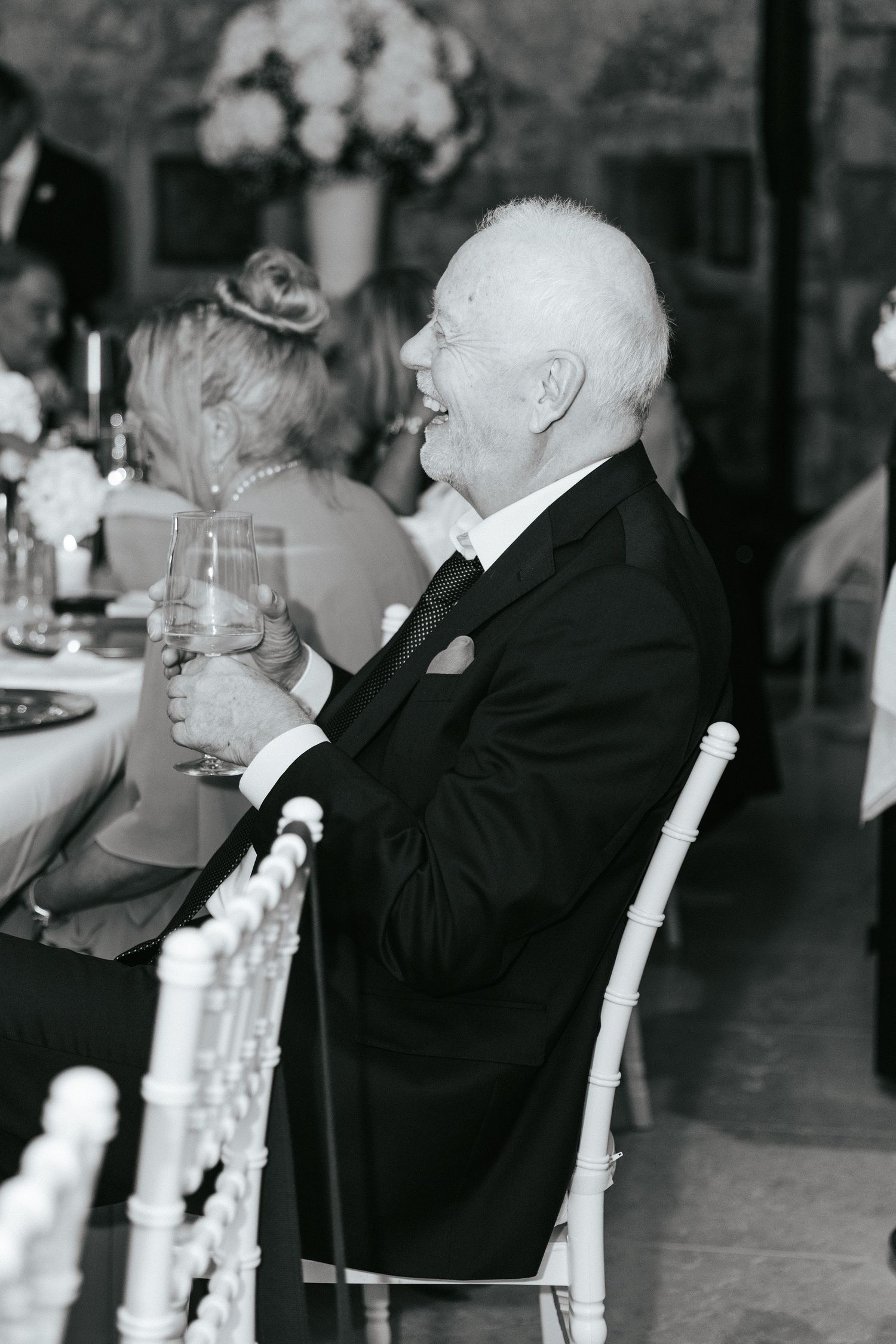 Black and white photo of the father of the groom enjoying a wedding reception dinner.