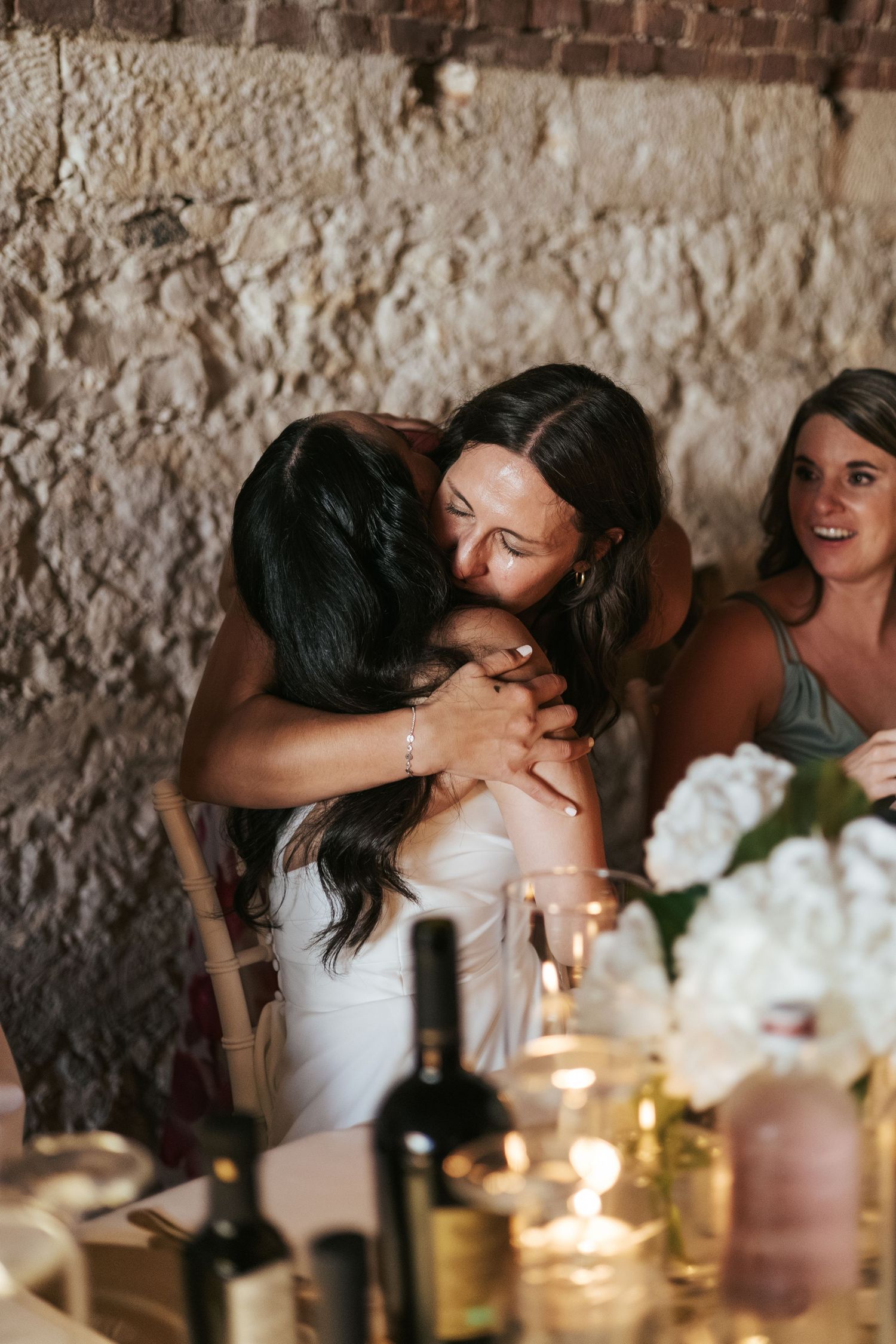 Candlelit wedding reception dinner in a rustic stone venue with guests sharing intimate moments.