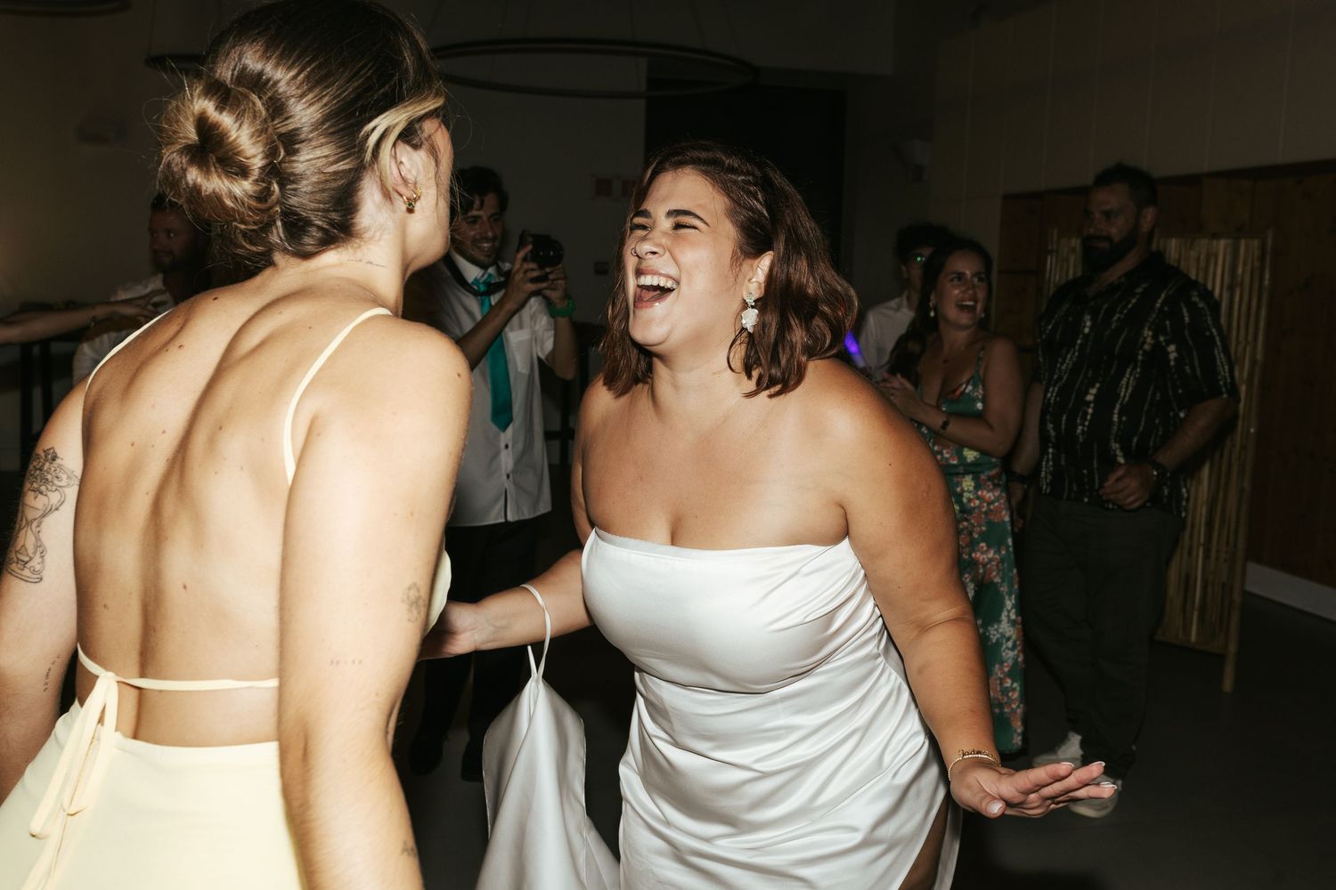 Wedding guests share a joyful moment of laughter during a reception celebration.
