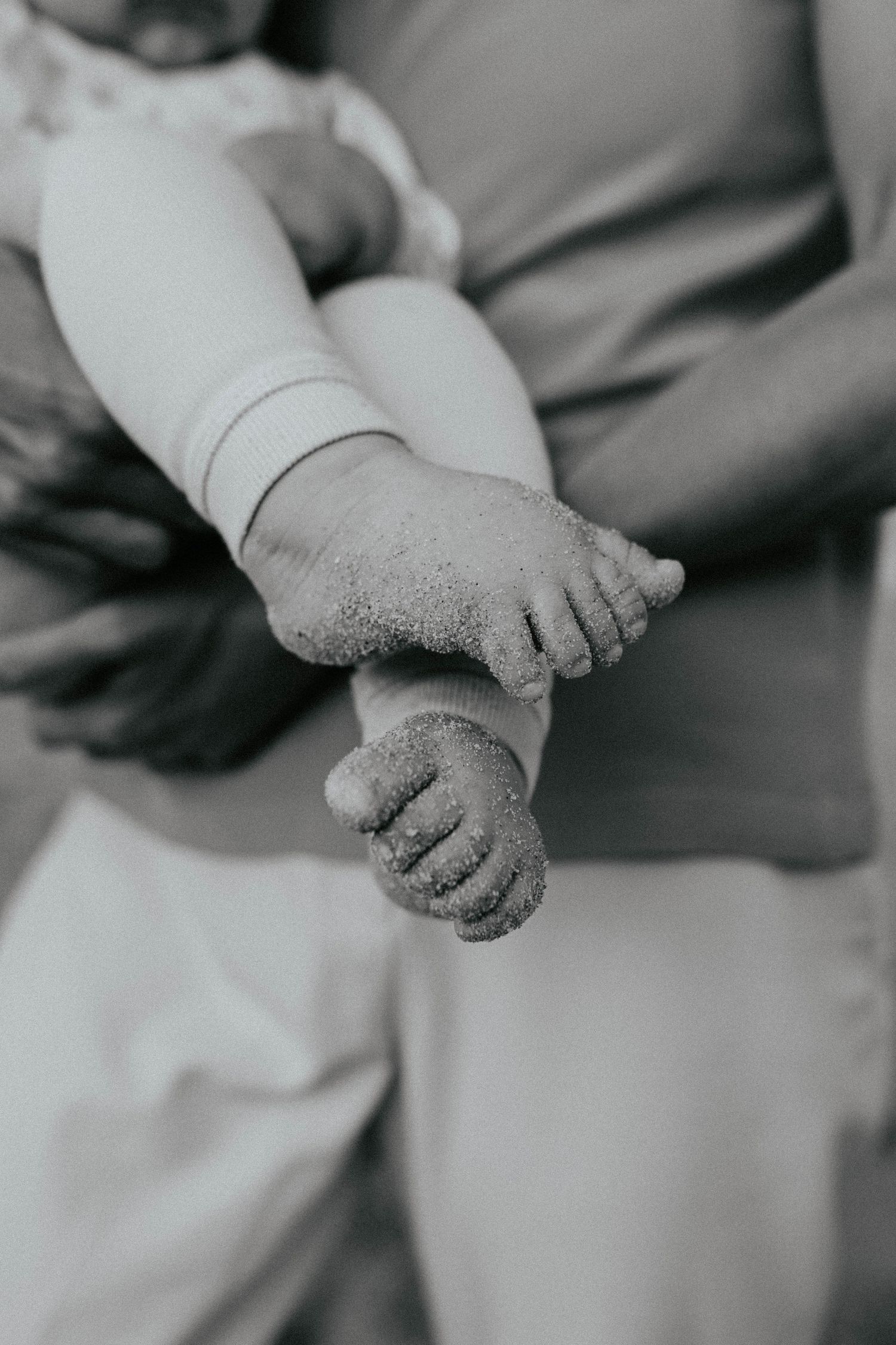 Black and white close-up photo of tiny baby feet covered in soft glitter or sparkles.