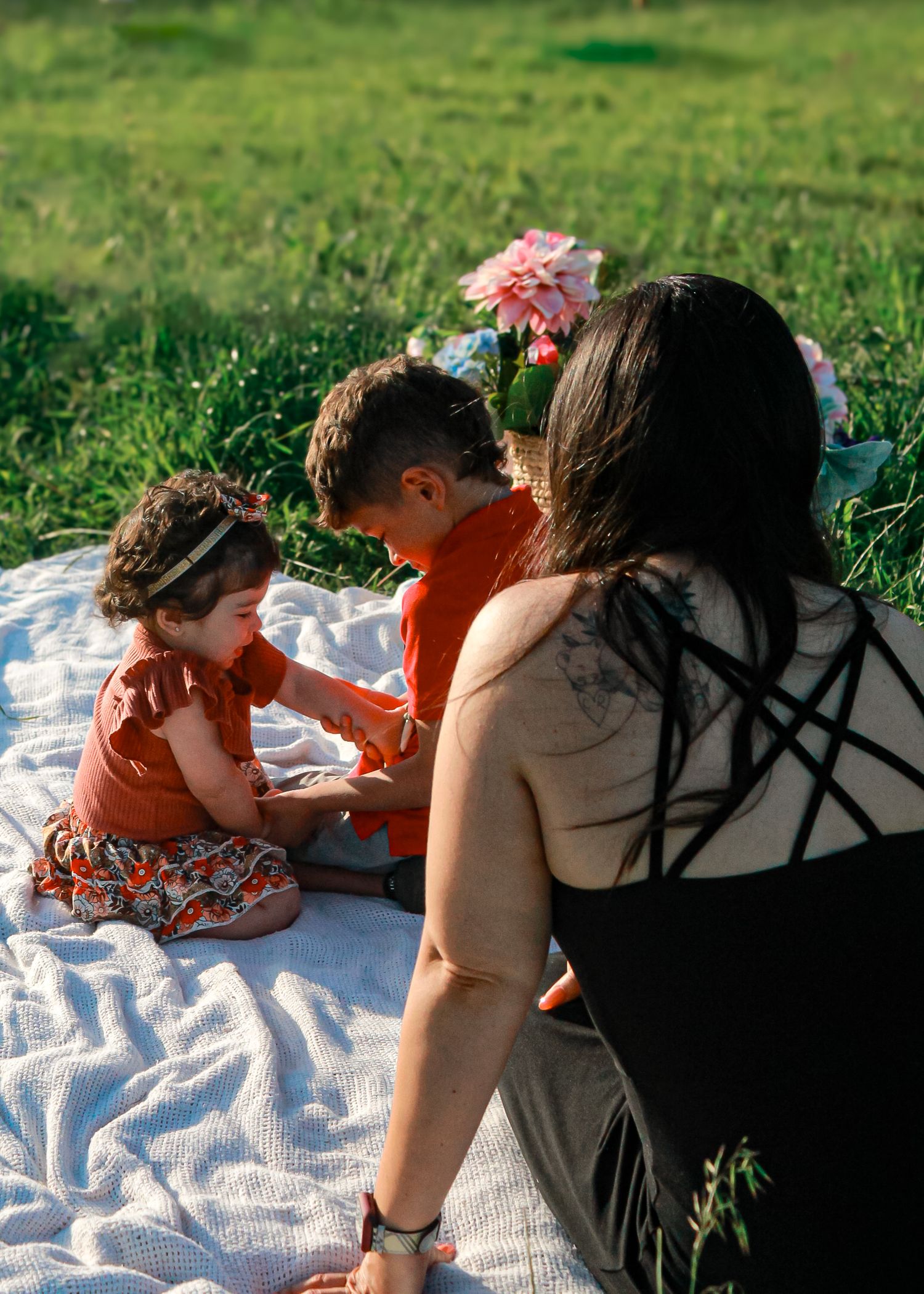 An intimate family moment captured on a white blanket during an outdoor photo session.