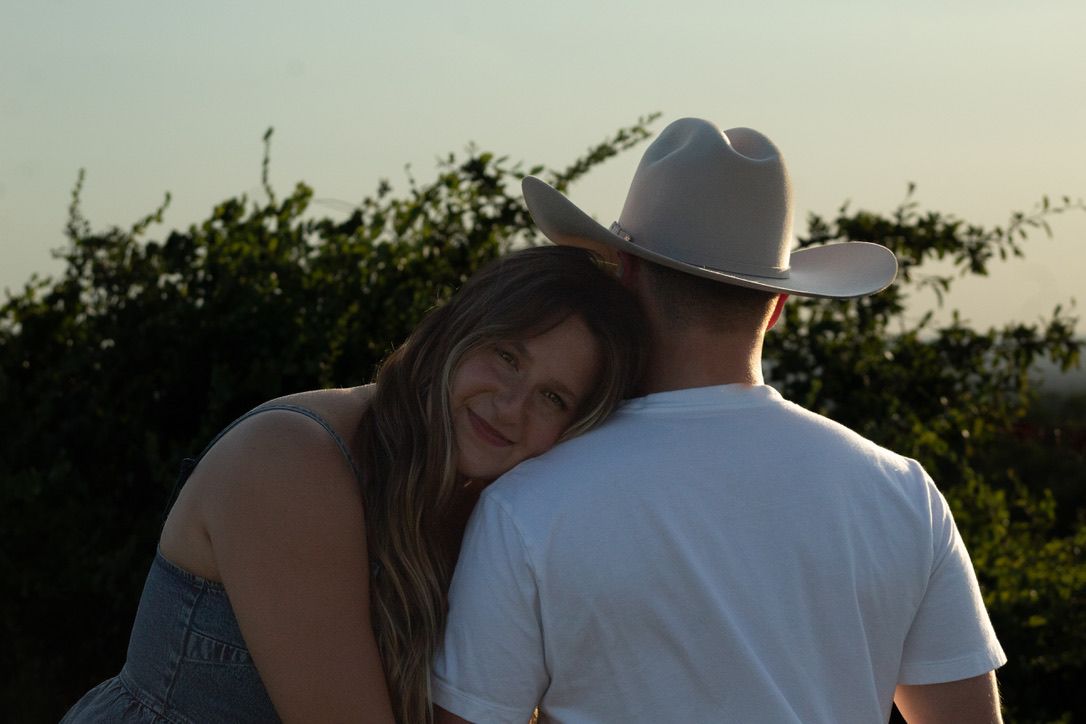 A couple in a scenic outdoor setting sharing an intimate moment during golden hour.