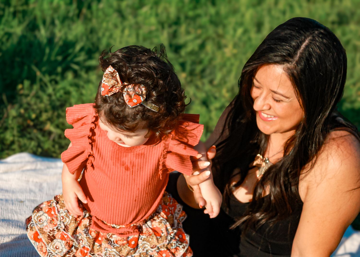 A touching candid moment in a garden setting with a small child wearing a coral-colored dress.