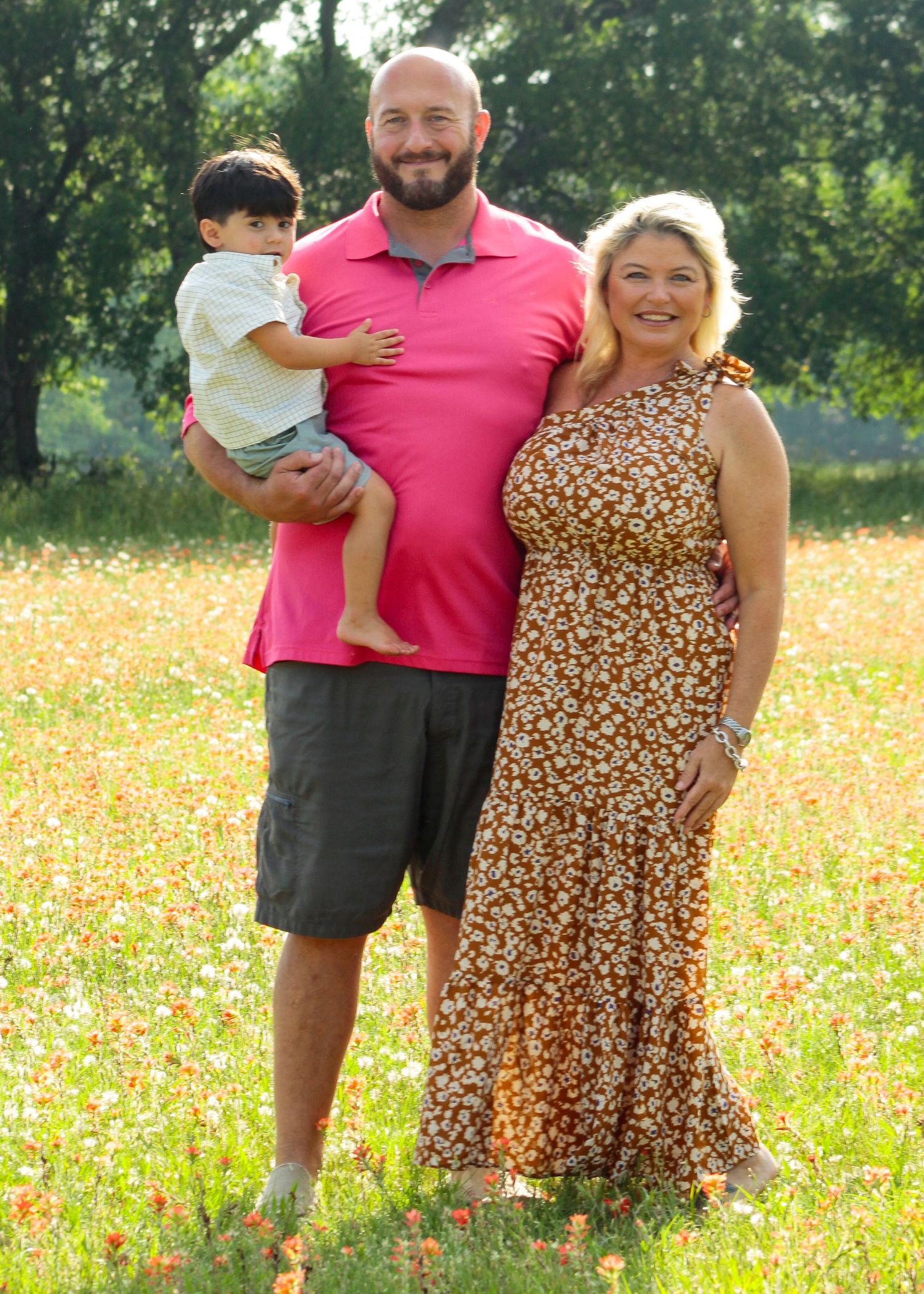 Family portrait in a sunny wildflower field wearing pink and floral outfits.