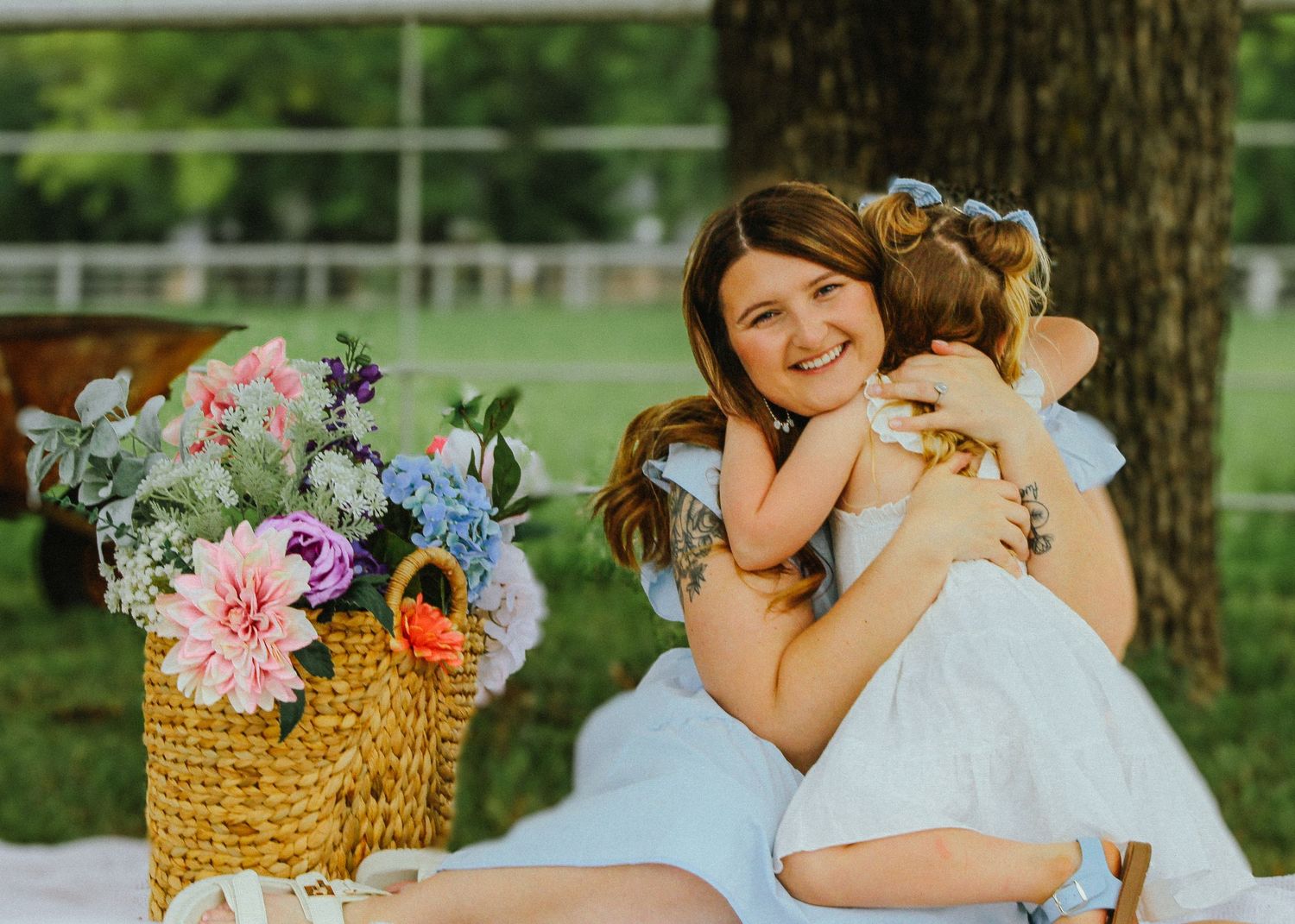 Sweet embrace captured during outdoor family photoshoot with floral basket arrangement.