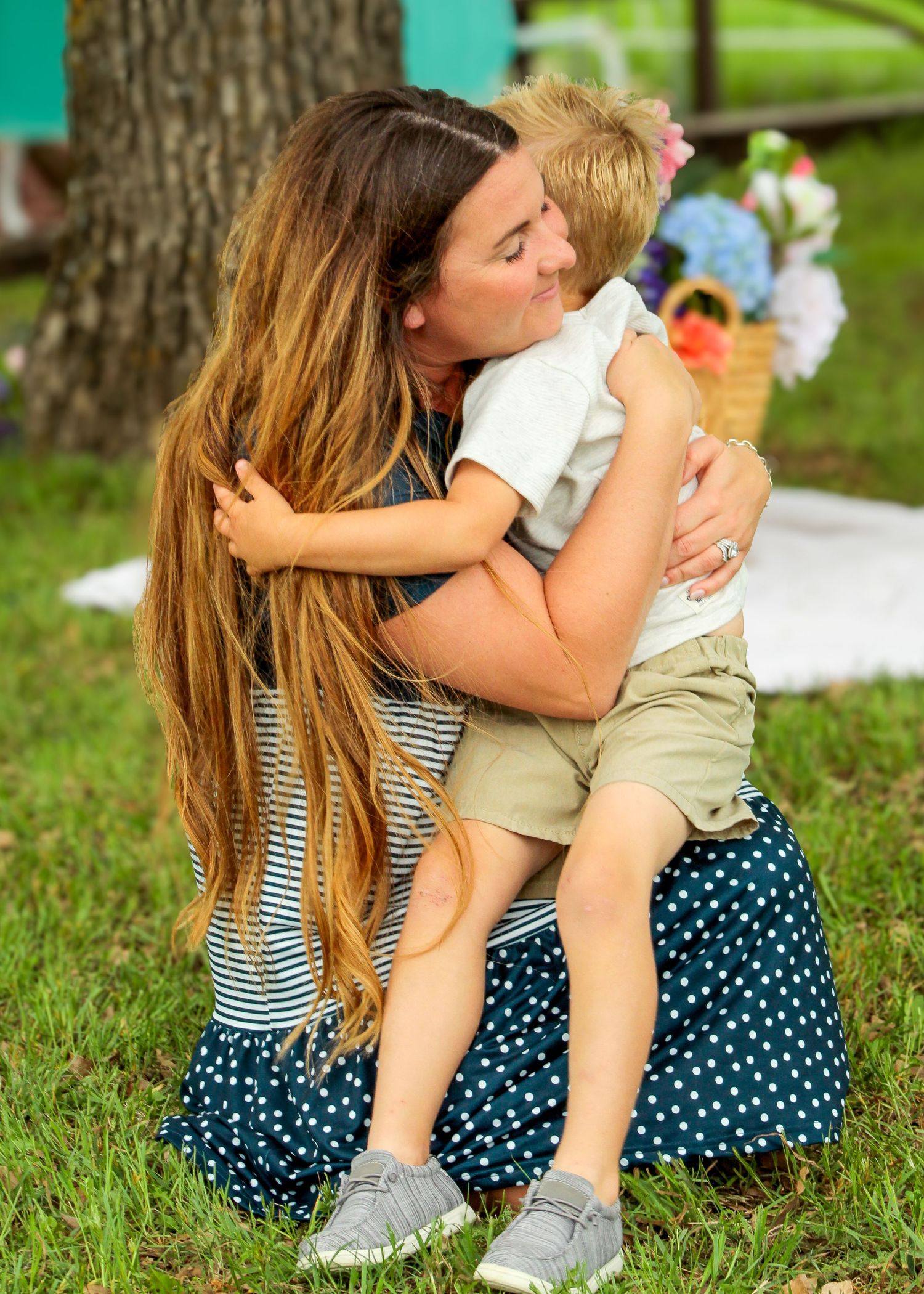 Loving embrace shared between parent and child outdoors against a tree backdrop.