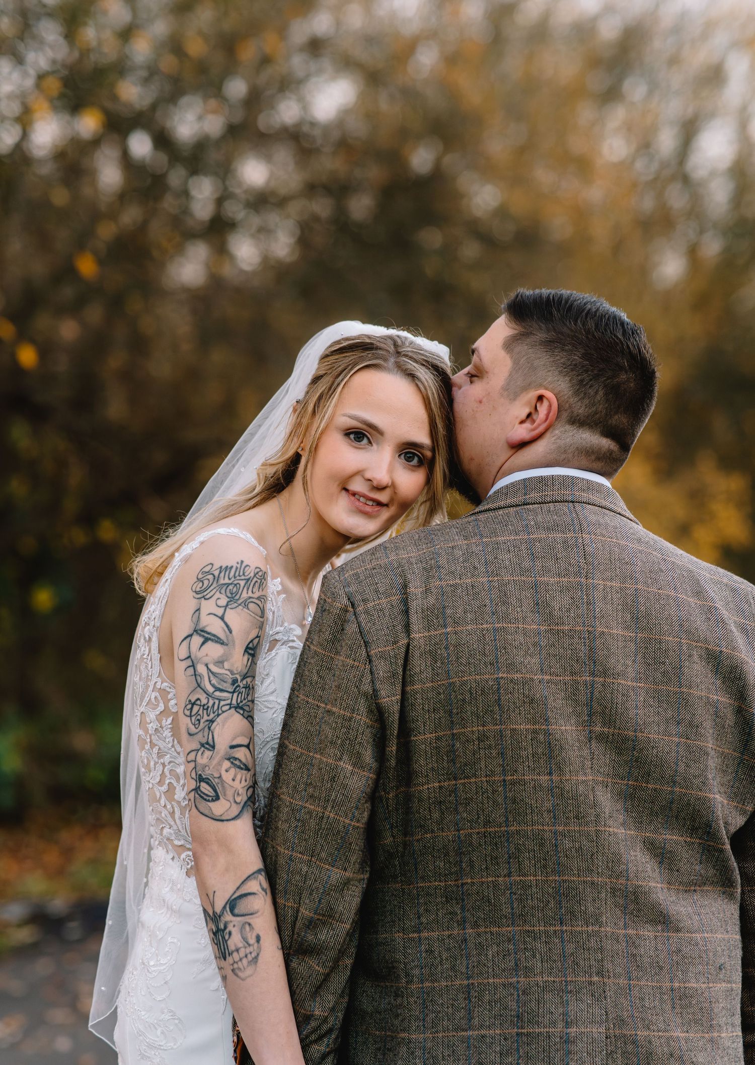 Candid wedding portrait of a bride smiling while leaning into the groom in a natural outdoor setting.