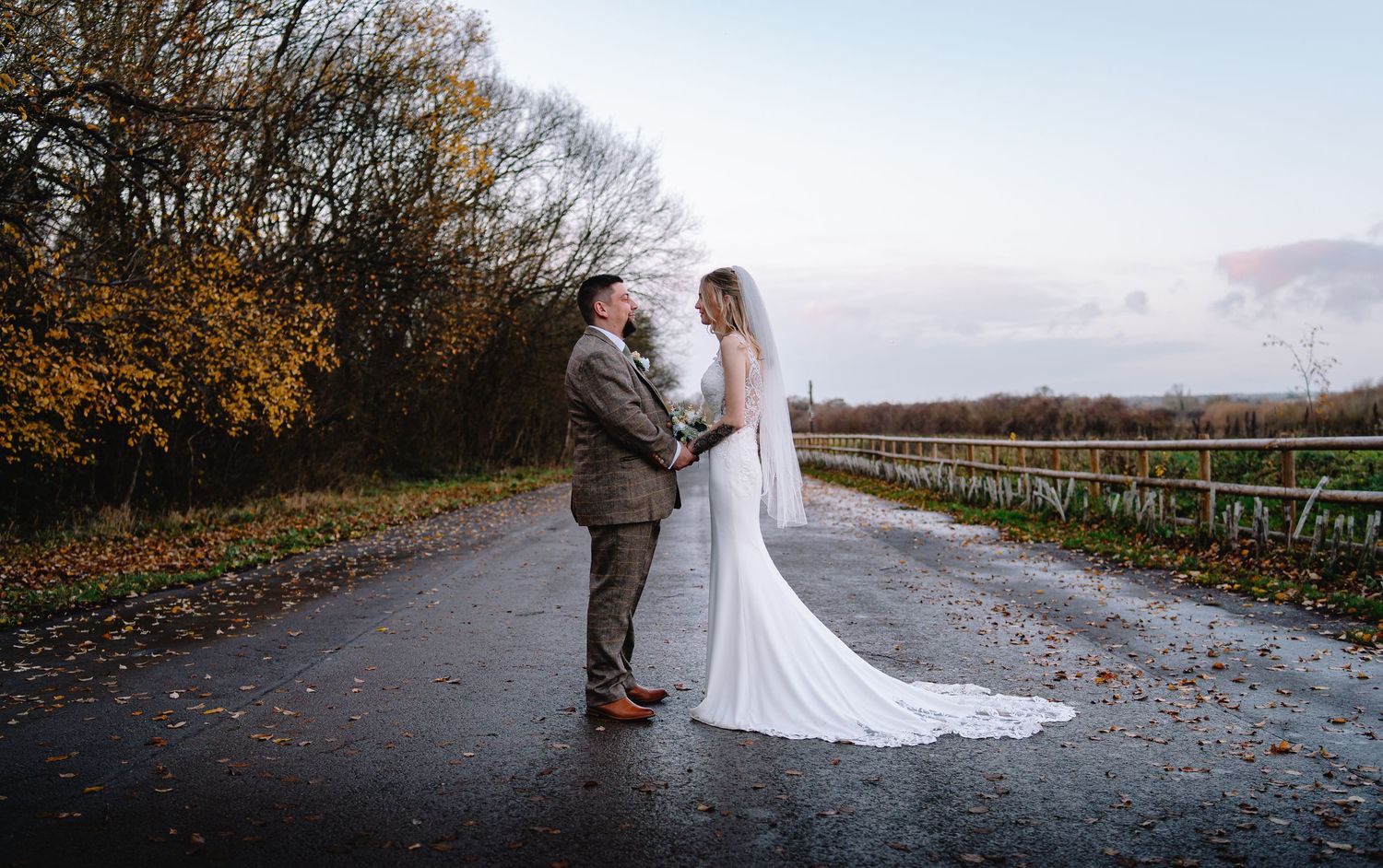 Bride and groom standing on a quiet road with dramatic skies, showcasing an elegant outdoor wedding portrait.