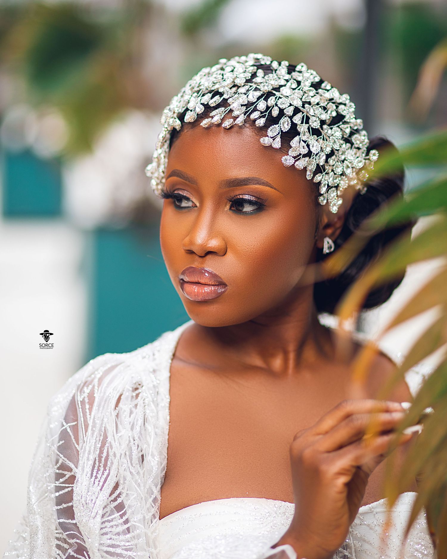 Beautiful bride wearing delicate white lace and an elegant crystal headpiece in a romantic outdoor portrait setting.