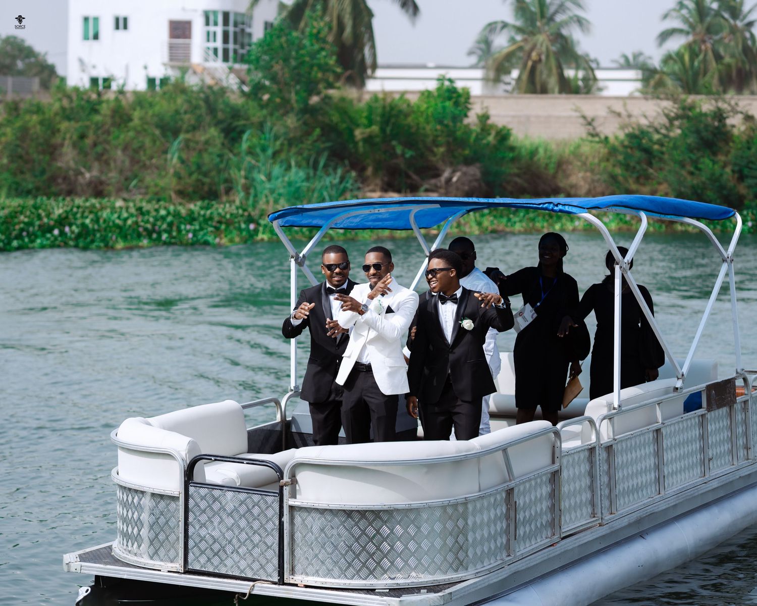 Group enjoying a pontoon boat ride on the water with palm trees visible in the background.