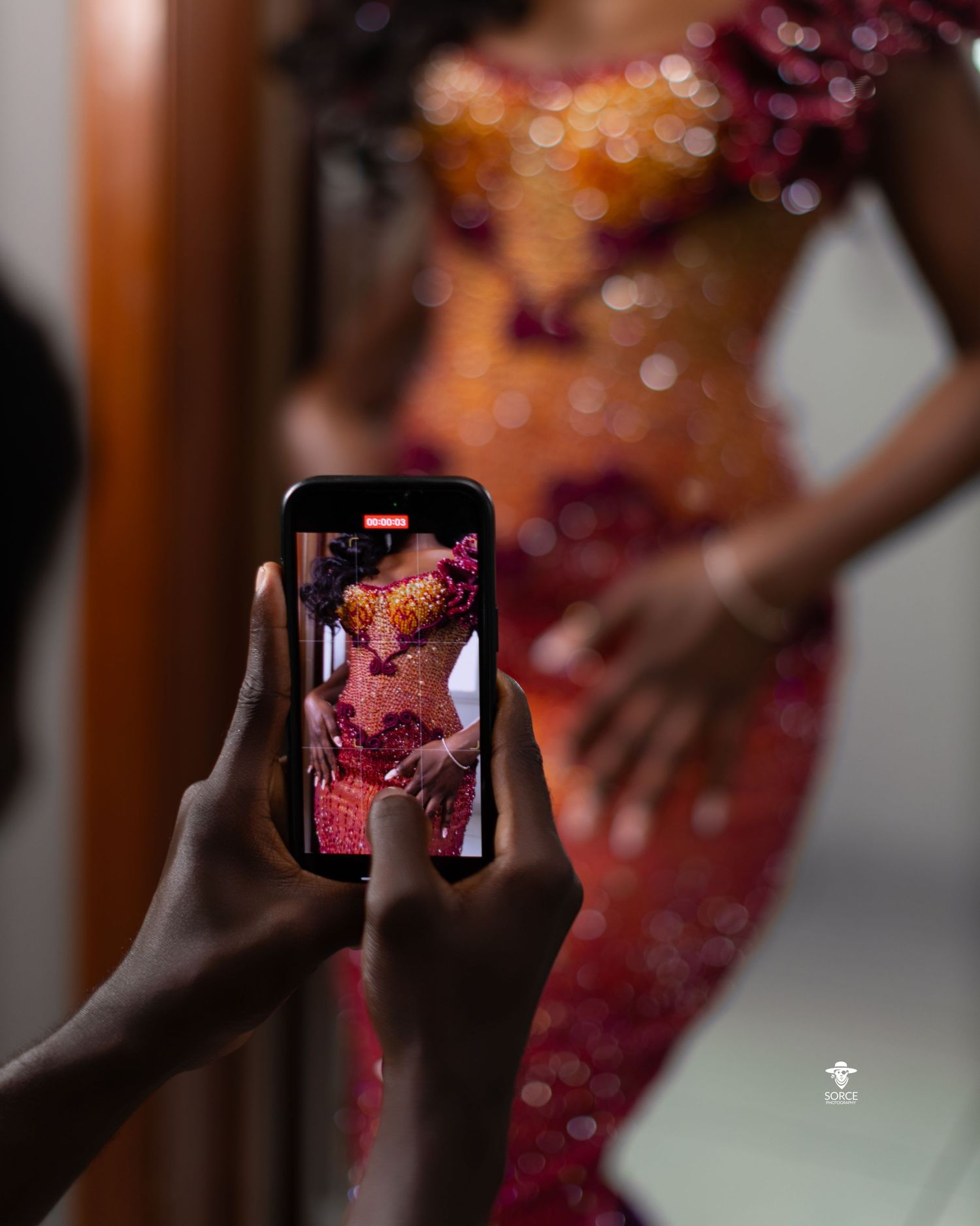Person in traditional South Asian attire being photographed with a smartphone camera.