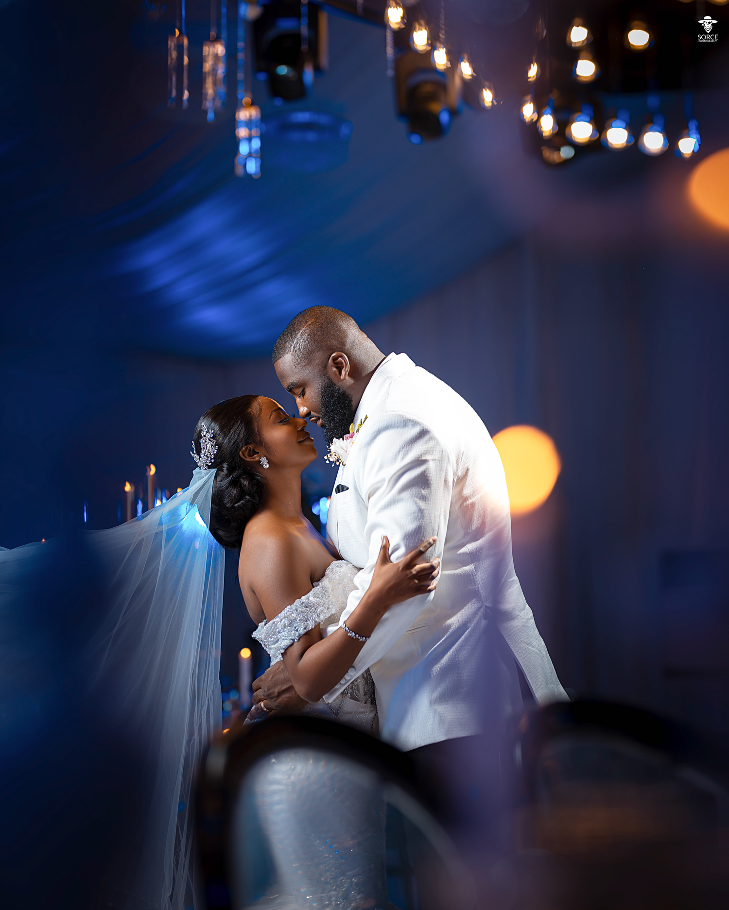 A romantic wedding couple shares their first dance under twinkling lights creating a dreamy blue atmosphere.