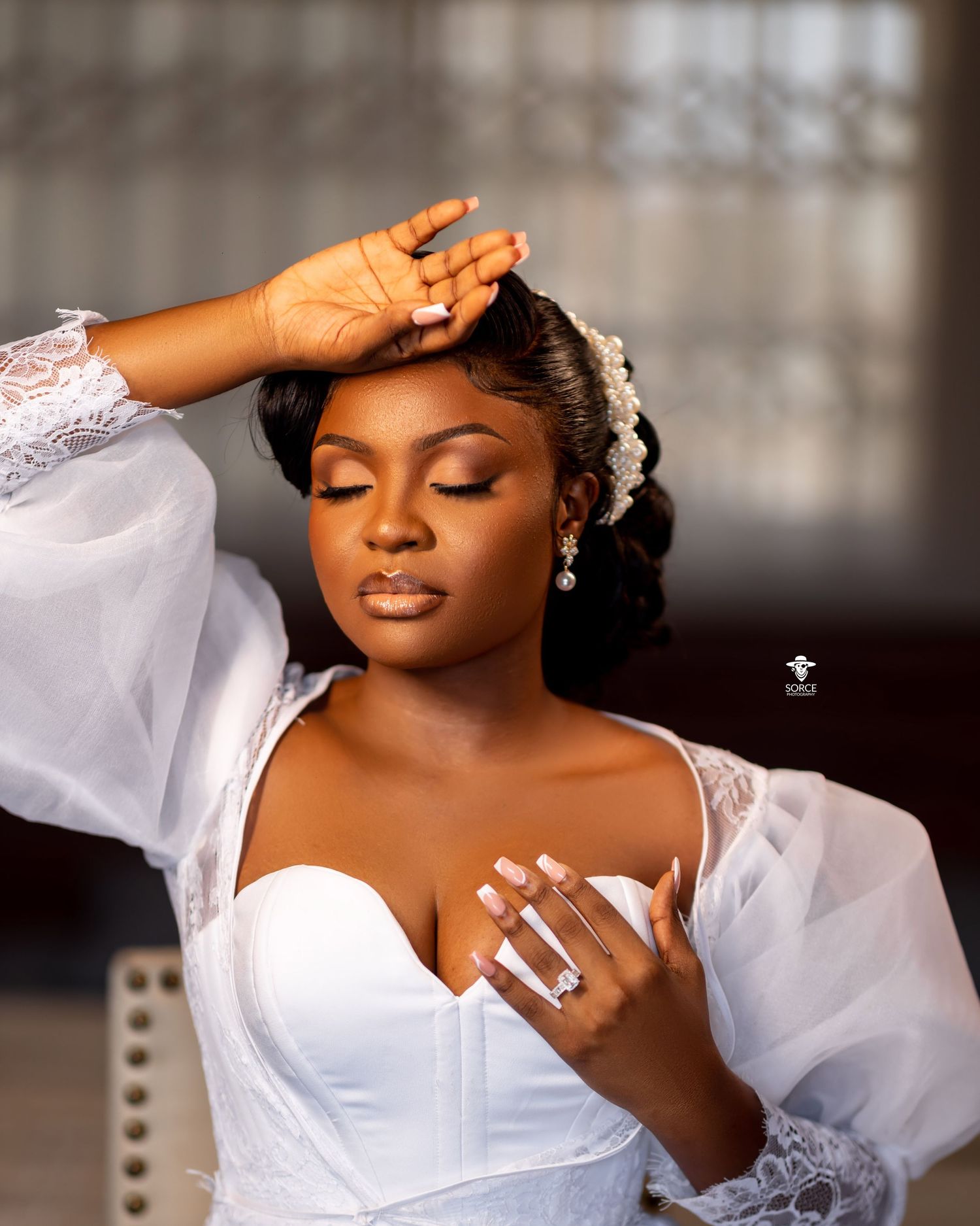 A bride in a white wedding dress with puffy sleeves poses elegantly against a textured backdrop.