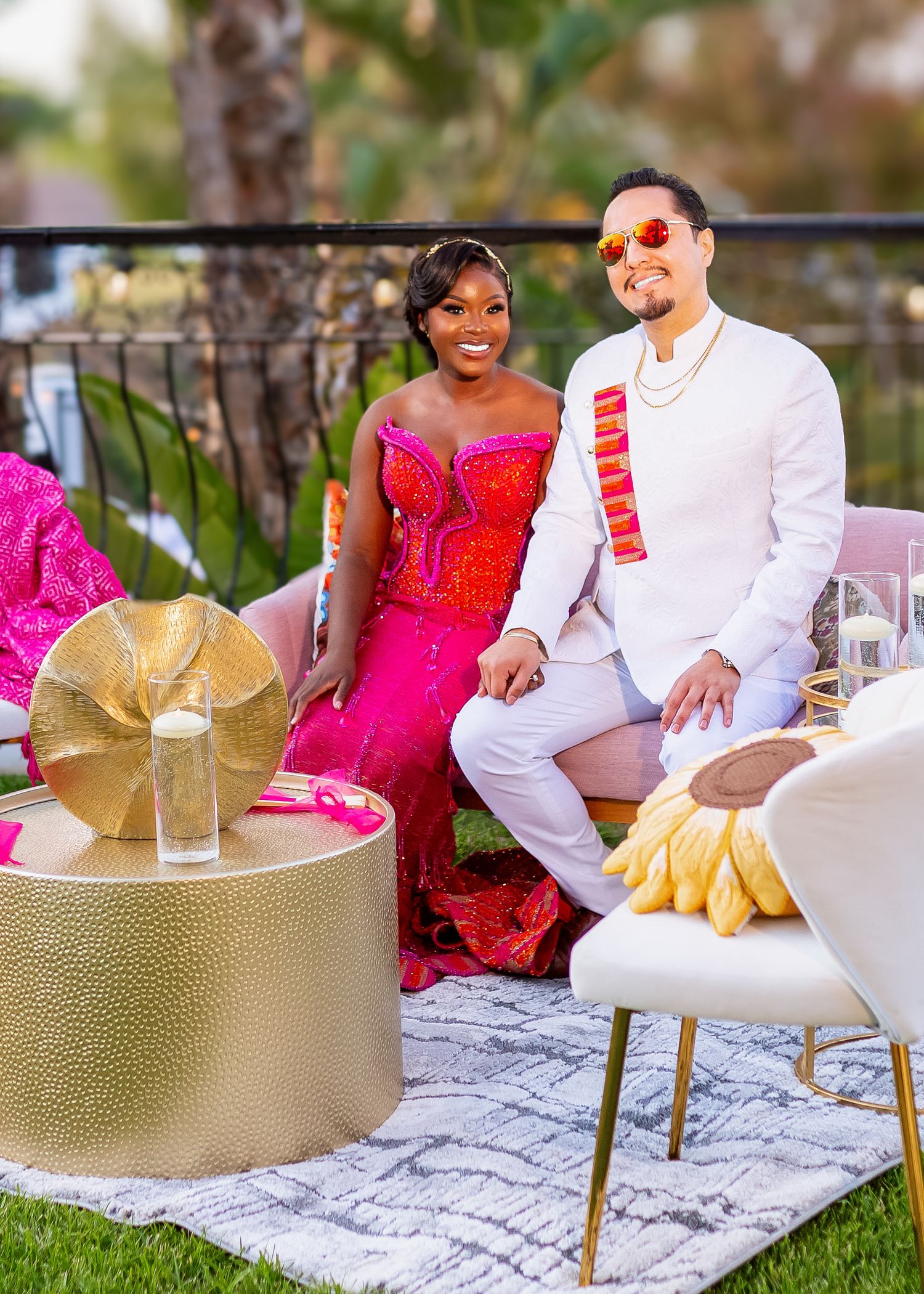 Couple relaxes on luxury outdoor furniture with gold accents and festive decorations.