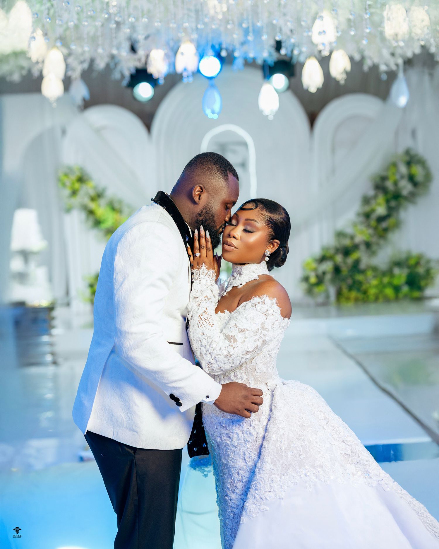 Elegant Black couple sharing a romantic moment in stunning white wedding attire at a luxurious venue.