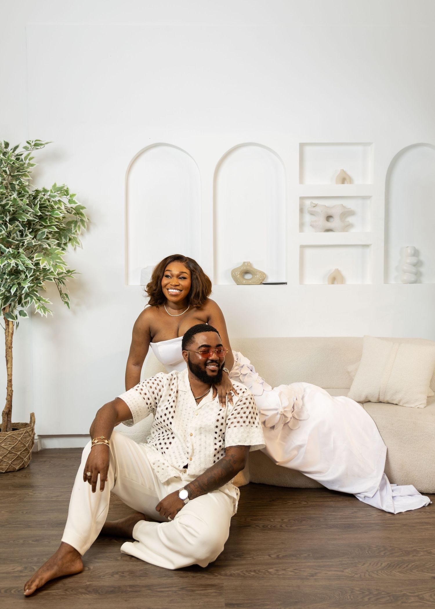 Couple in white outfits lounging together in modern minimalist living room.