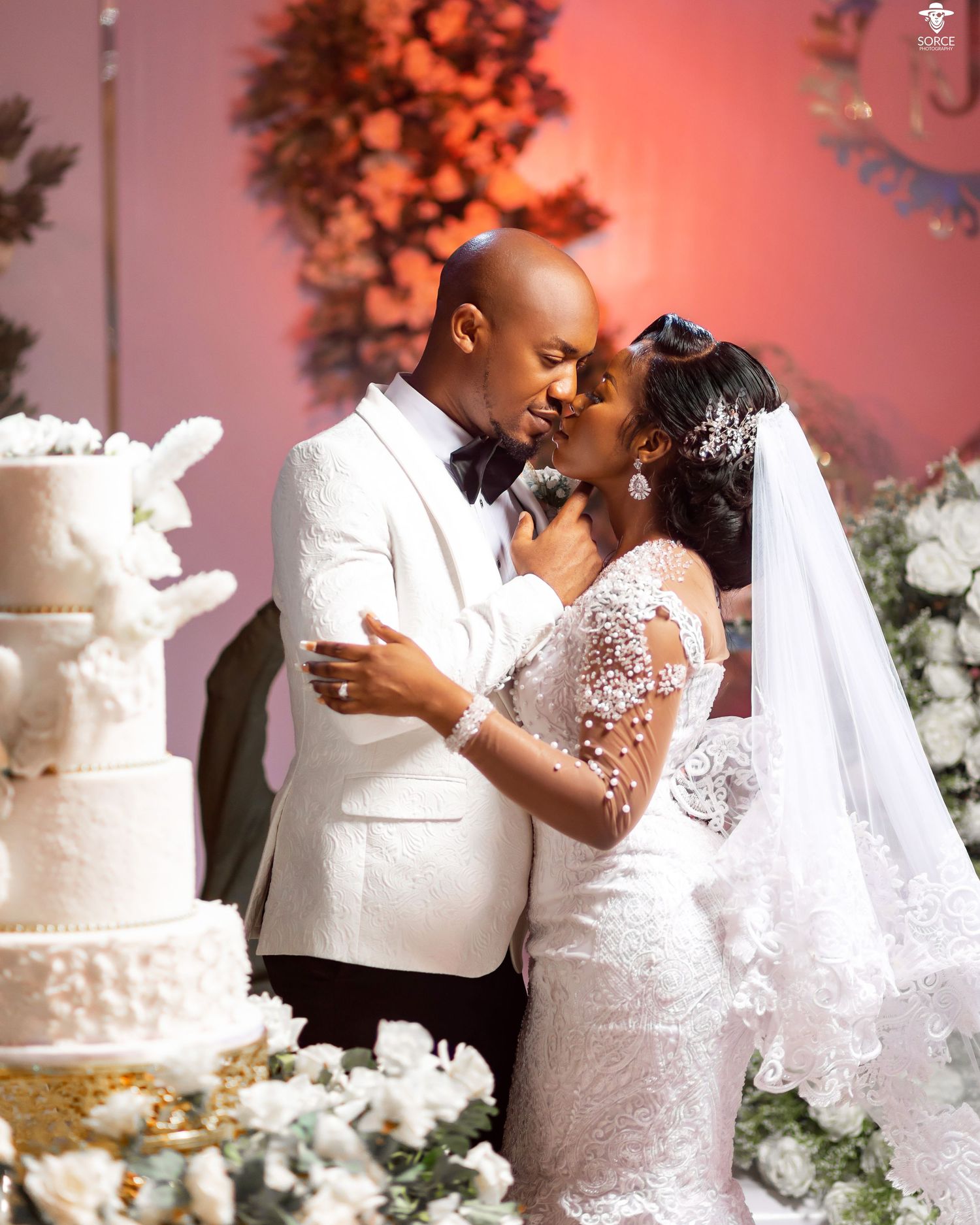 A collection of wedding moments featuring an intricate white lace dress and elegant tiered cake at a reception with coral lighting.