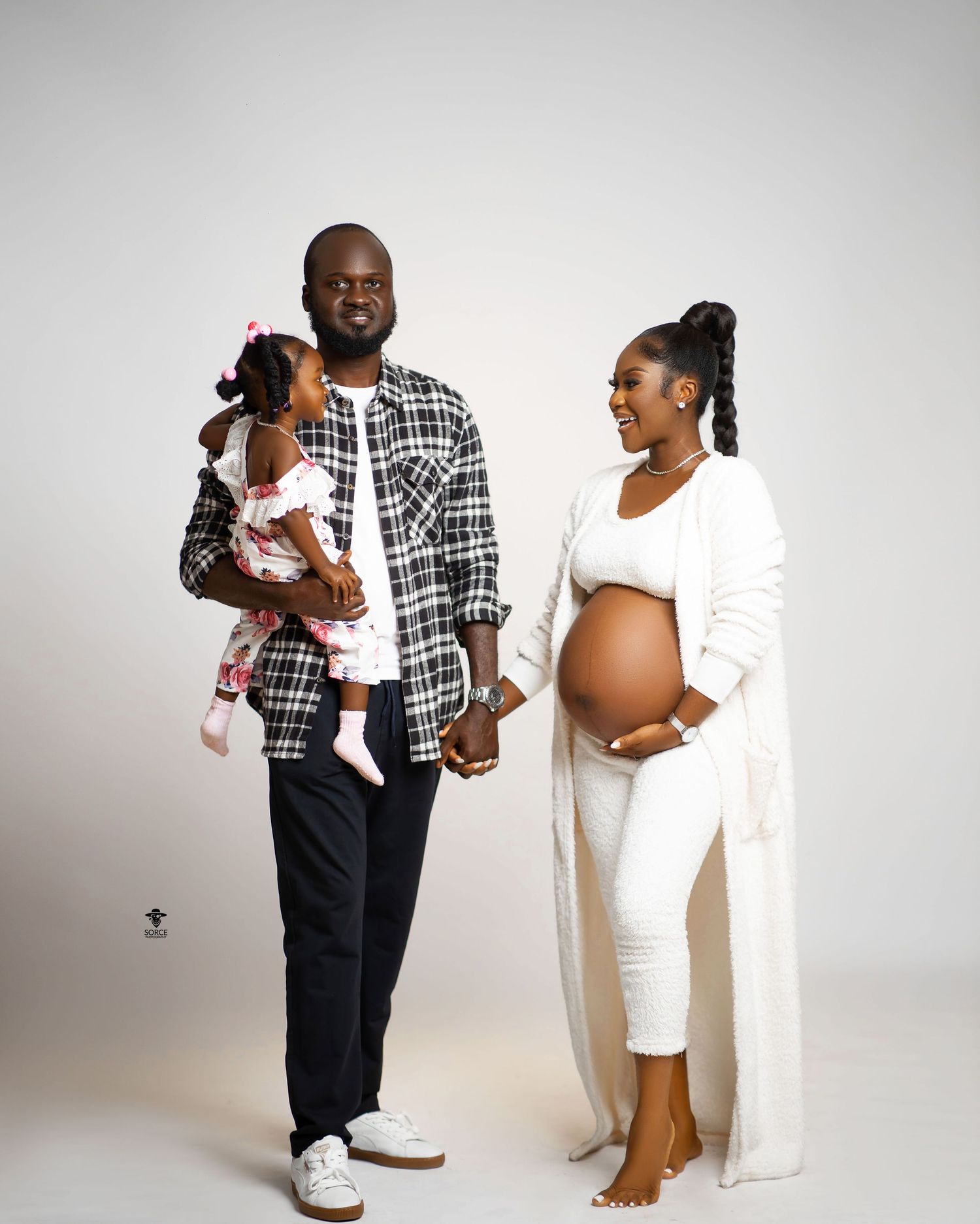 A couple in black and white outfits pose together for a series of maternity and newborn photoshoot portraits.