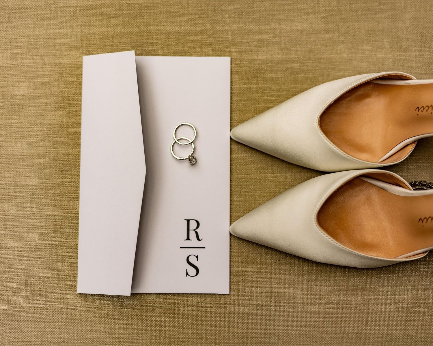 A row of elegant white pointed-toe shoes and minimalist decor arranged on a beige linen background.