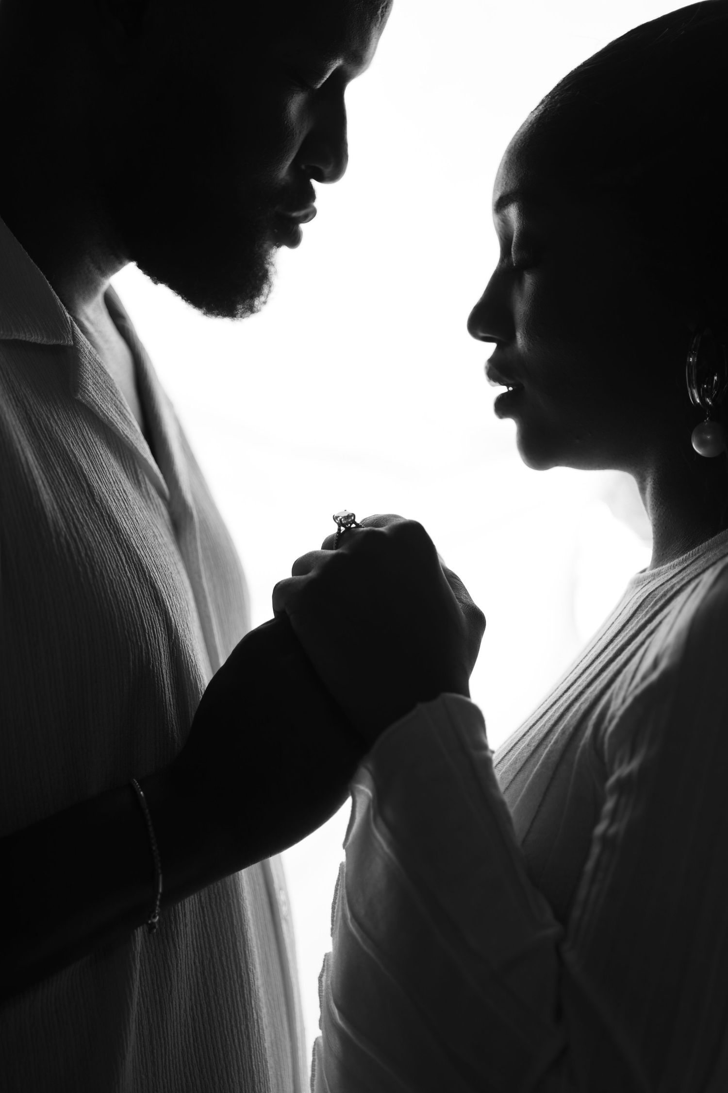 Black and white silhouette series showing two figures in intimate poses against a bright background.