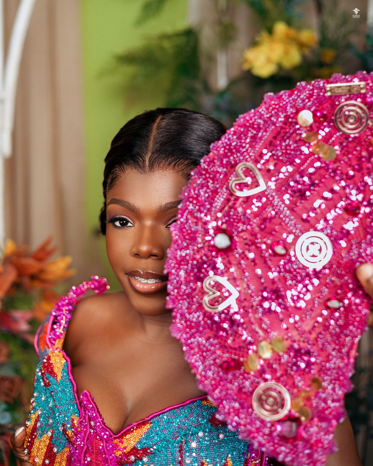 Vibrant pink beaded fan adorned with pearls and decorative elements creates stunning contrast with turquoise formal attire.