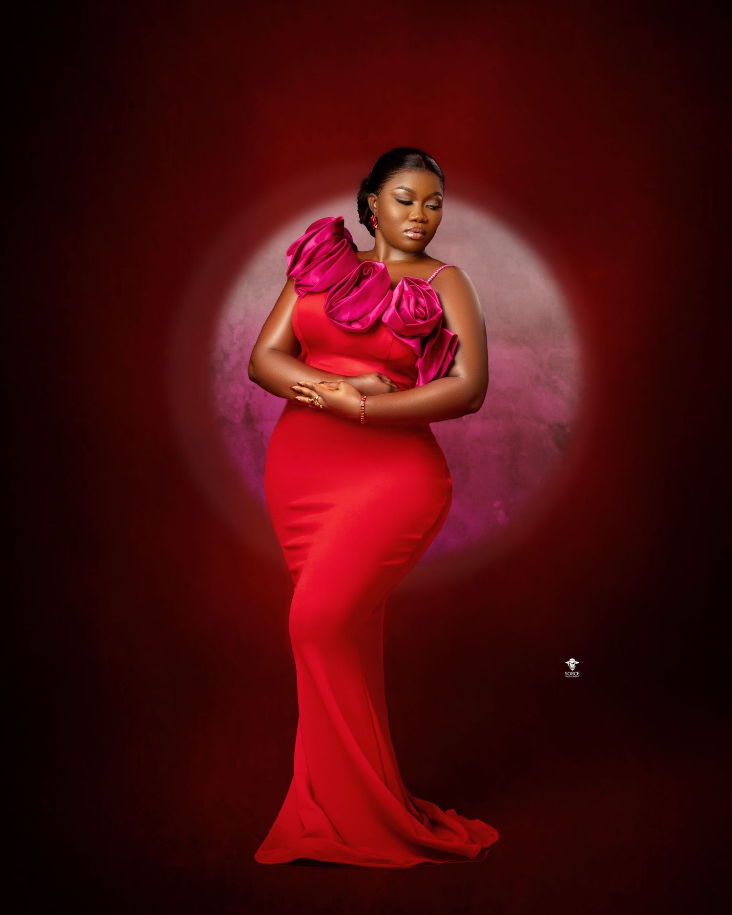 Figure in a flowing red gown poses dramatically against dark background with moody red lighting effects.