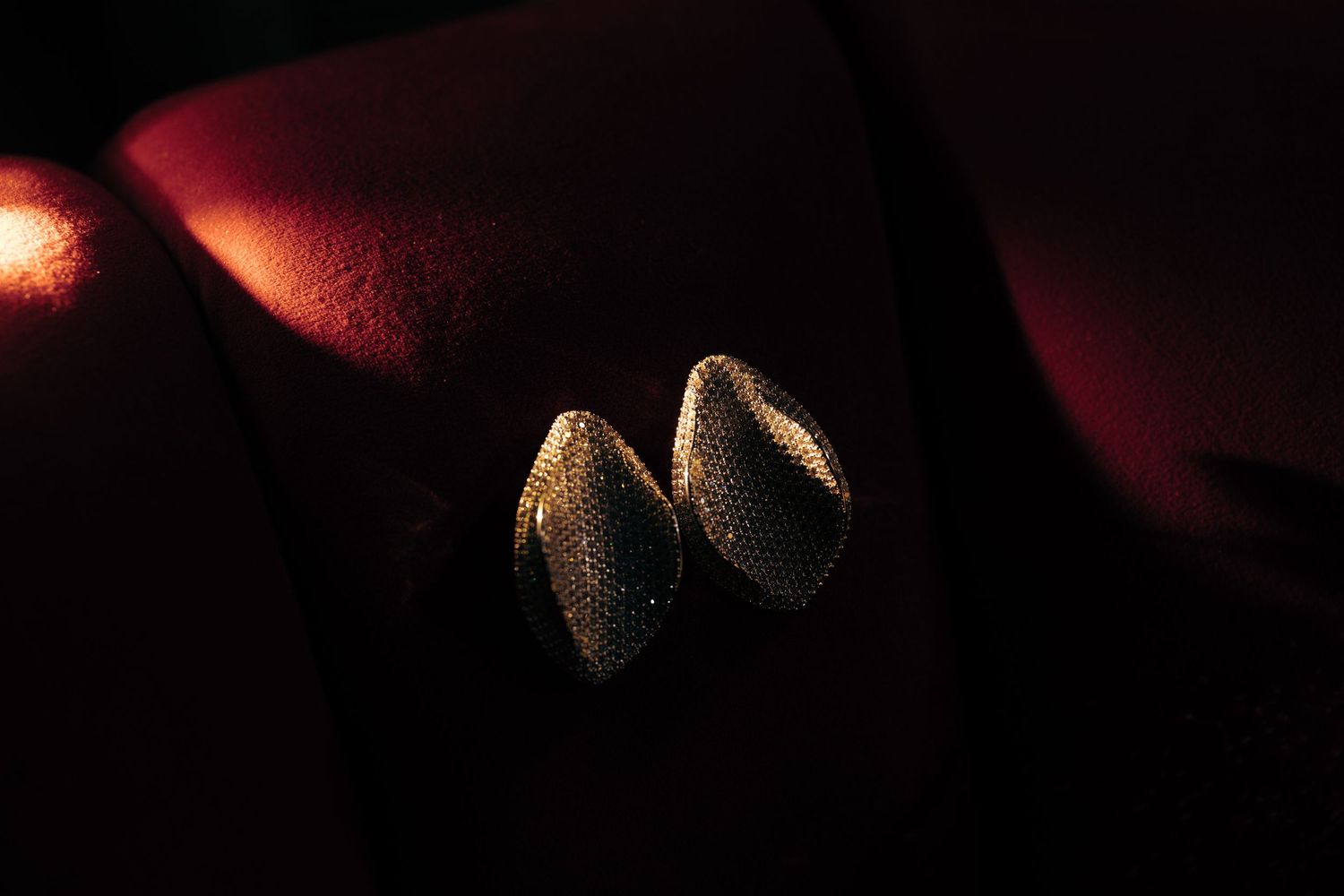 Closeup photo of two pistachios in their shells on dark background with dramatic lighting and shadows.