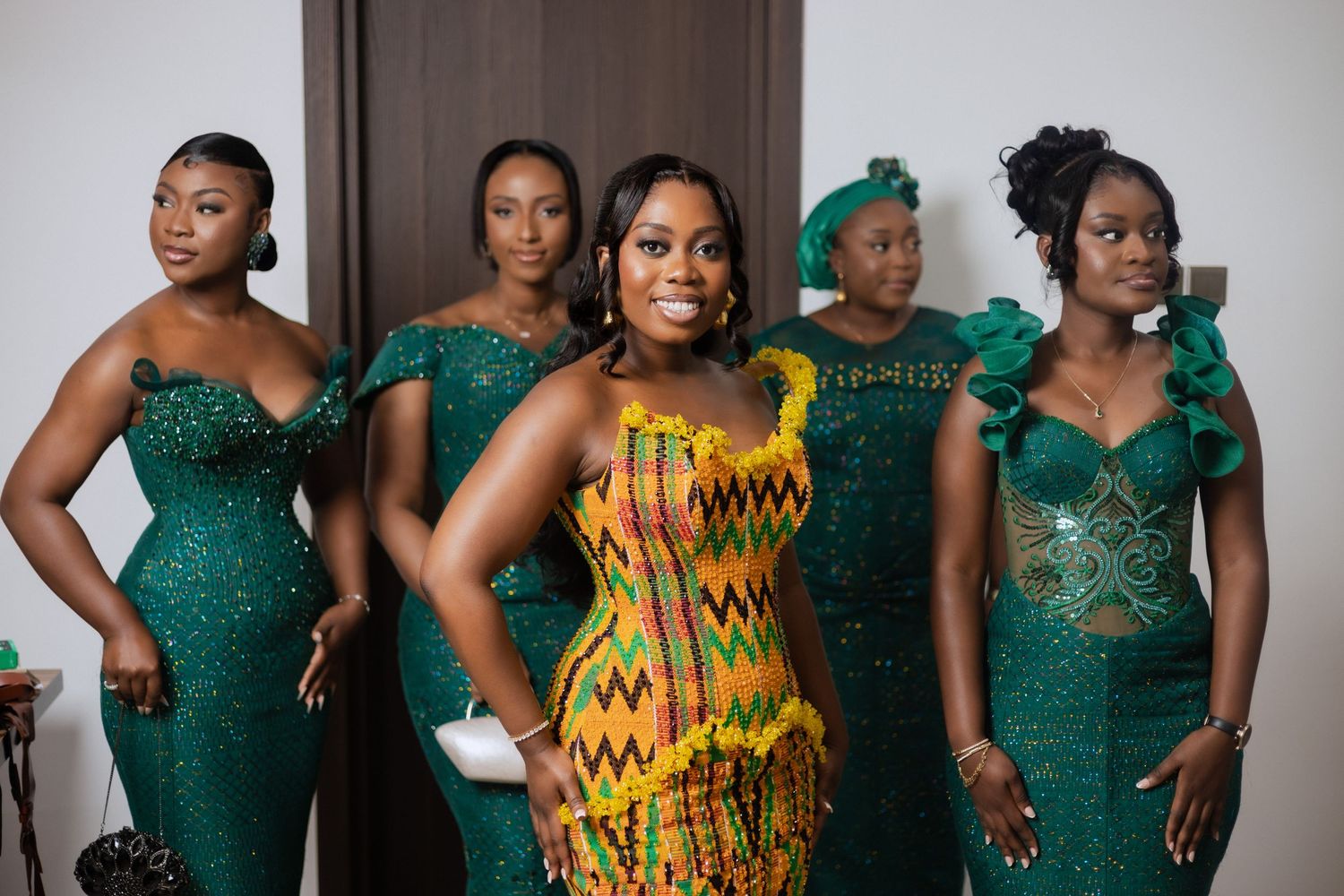 Wedding party in elegant emerald green gowns and yellow kente cloth dress.