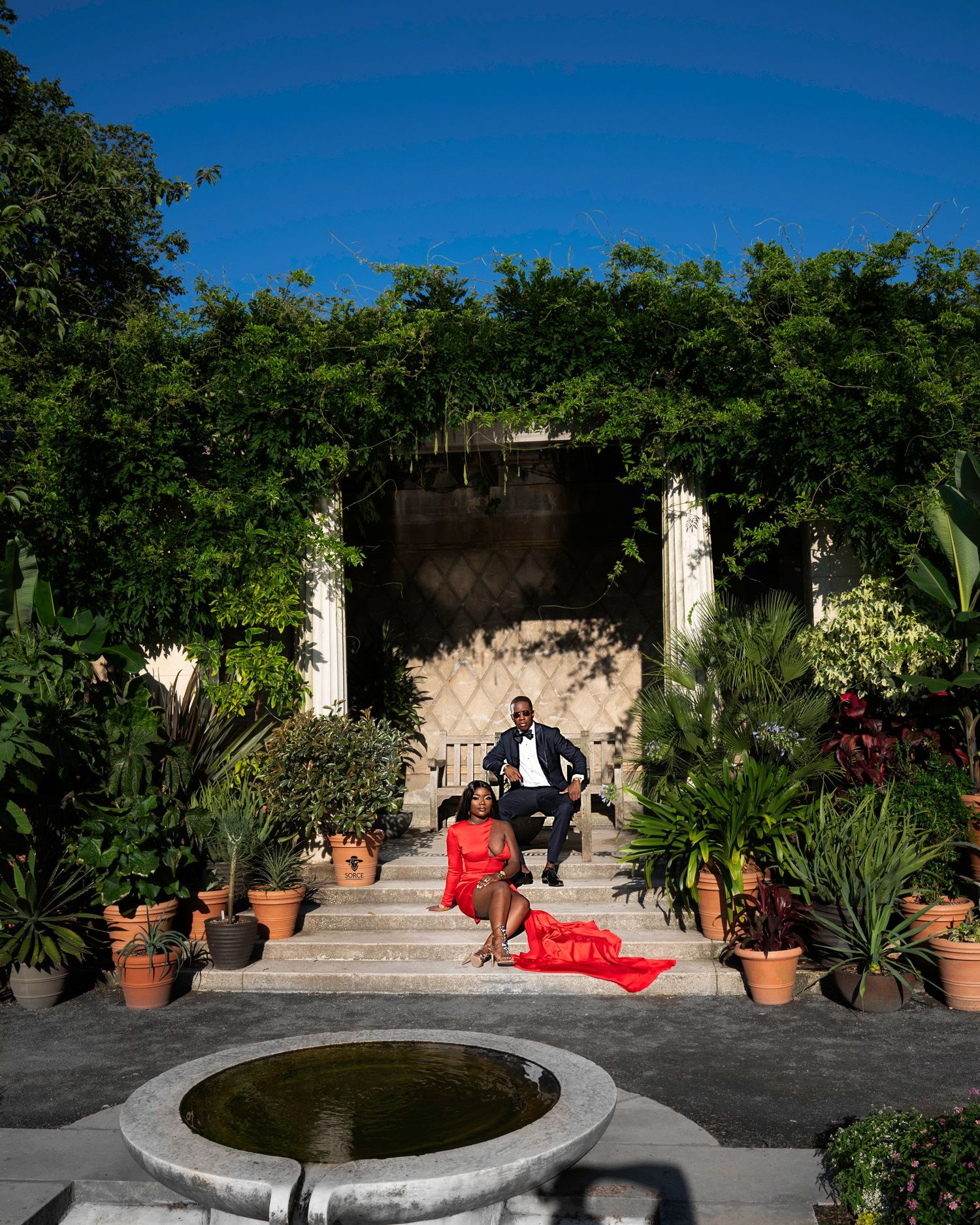 Wedding photo shoot in lush garden setting with stone steps and potted plants.